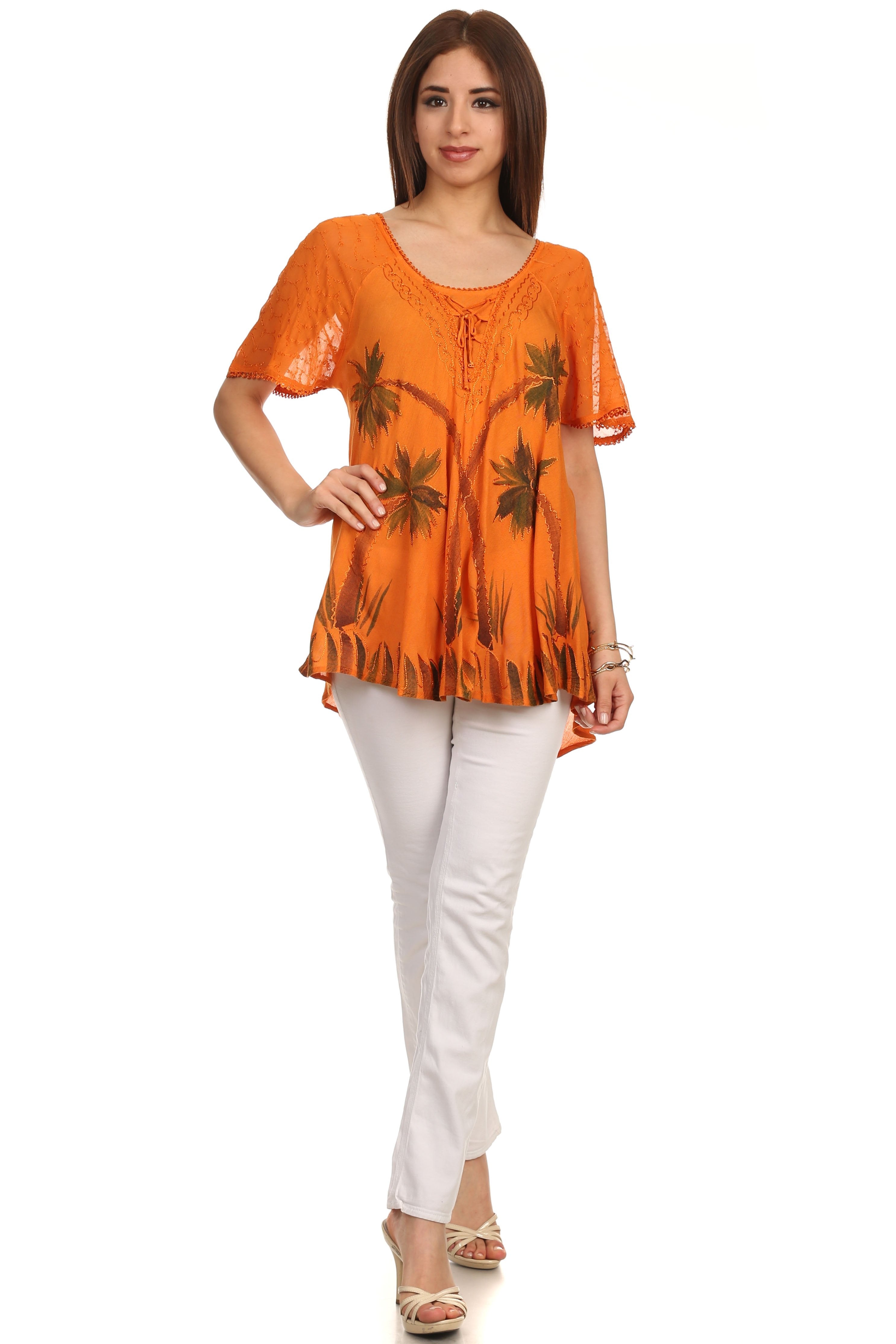 Woman wearing an orange blouse with palm tree pattern and white pants on a white background