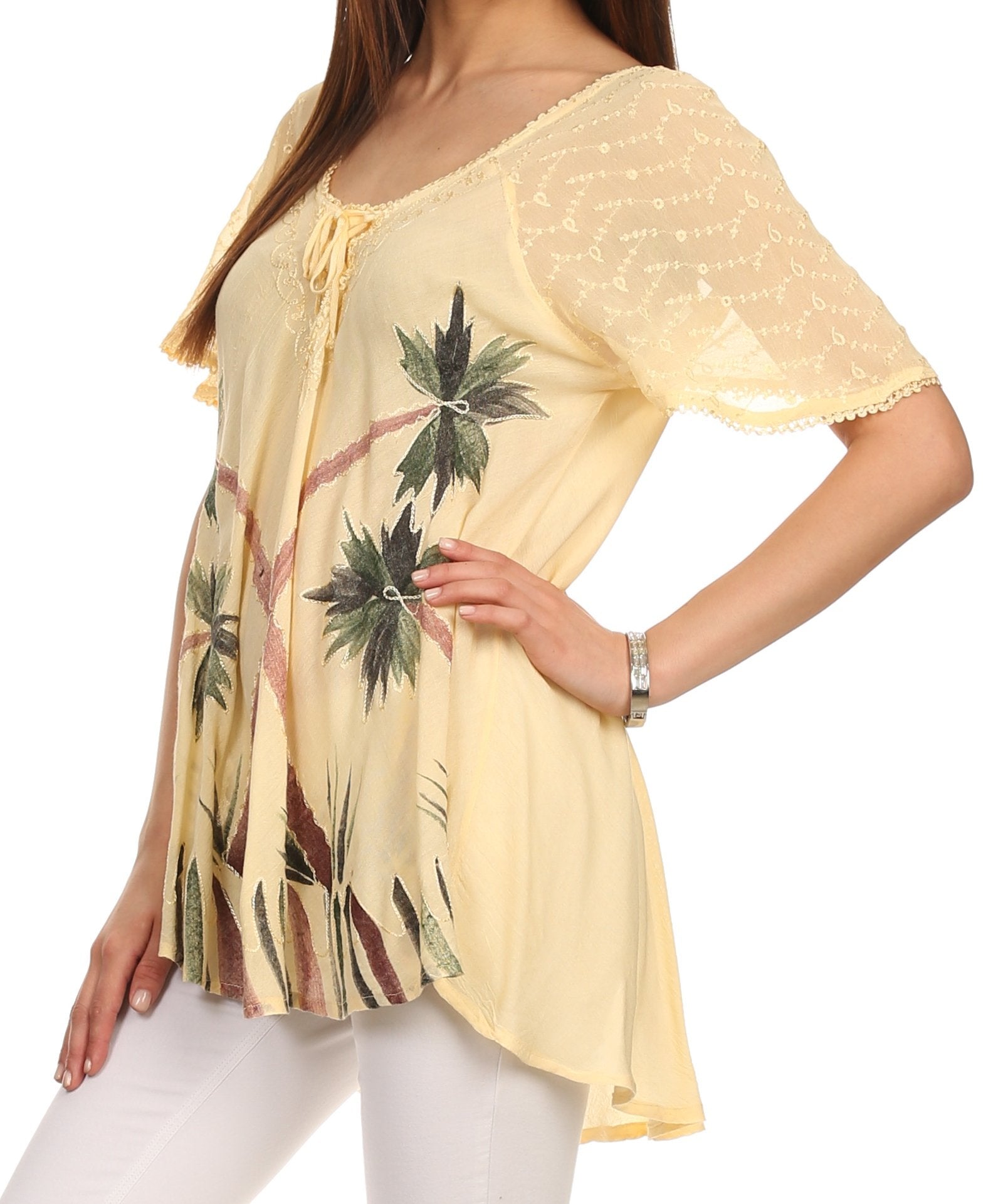 Woman wearing a yellow floral print top with white pants on a white background