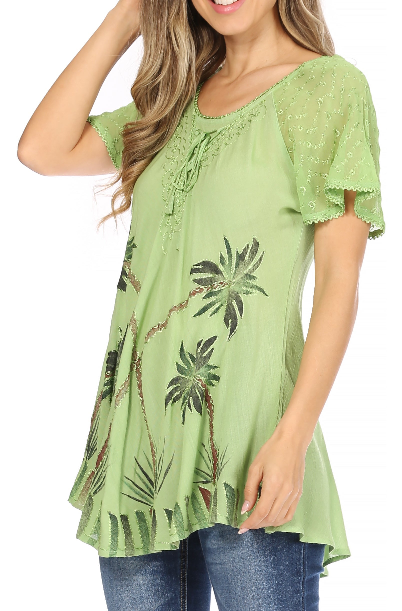 Woman wearing a green floral-patterned top with blue jeans on a white background