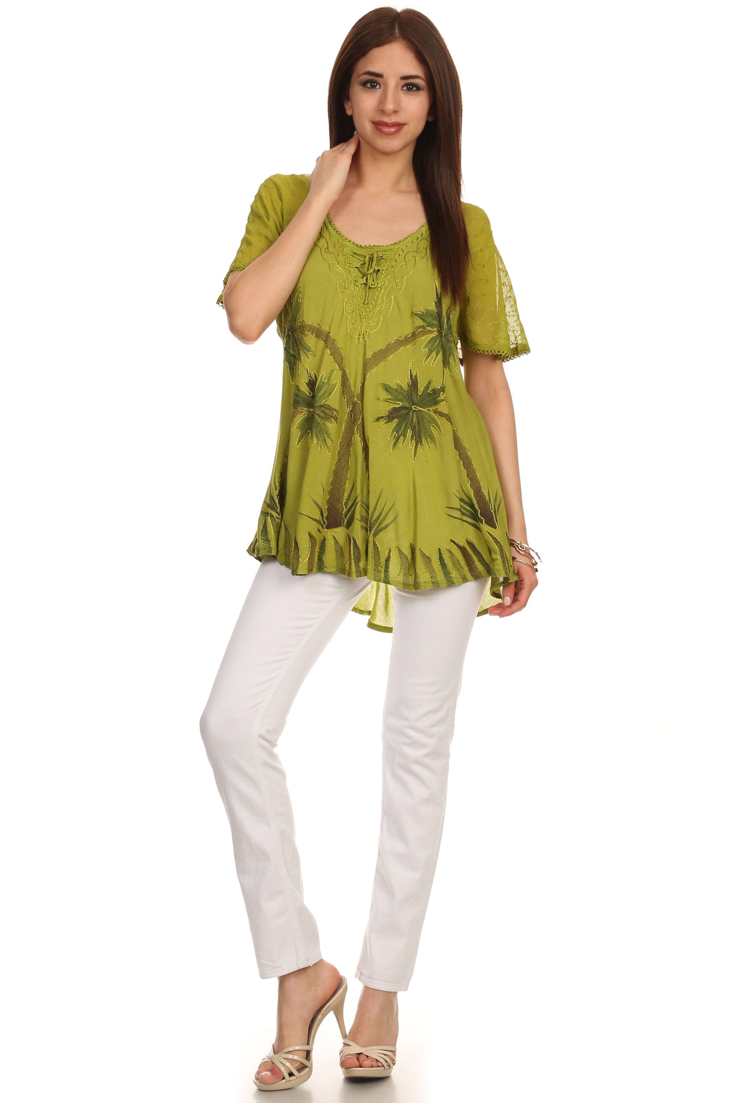 Woman wearing a green printed top and white pants on a white background