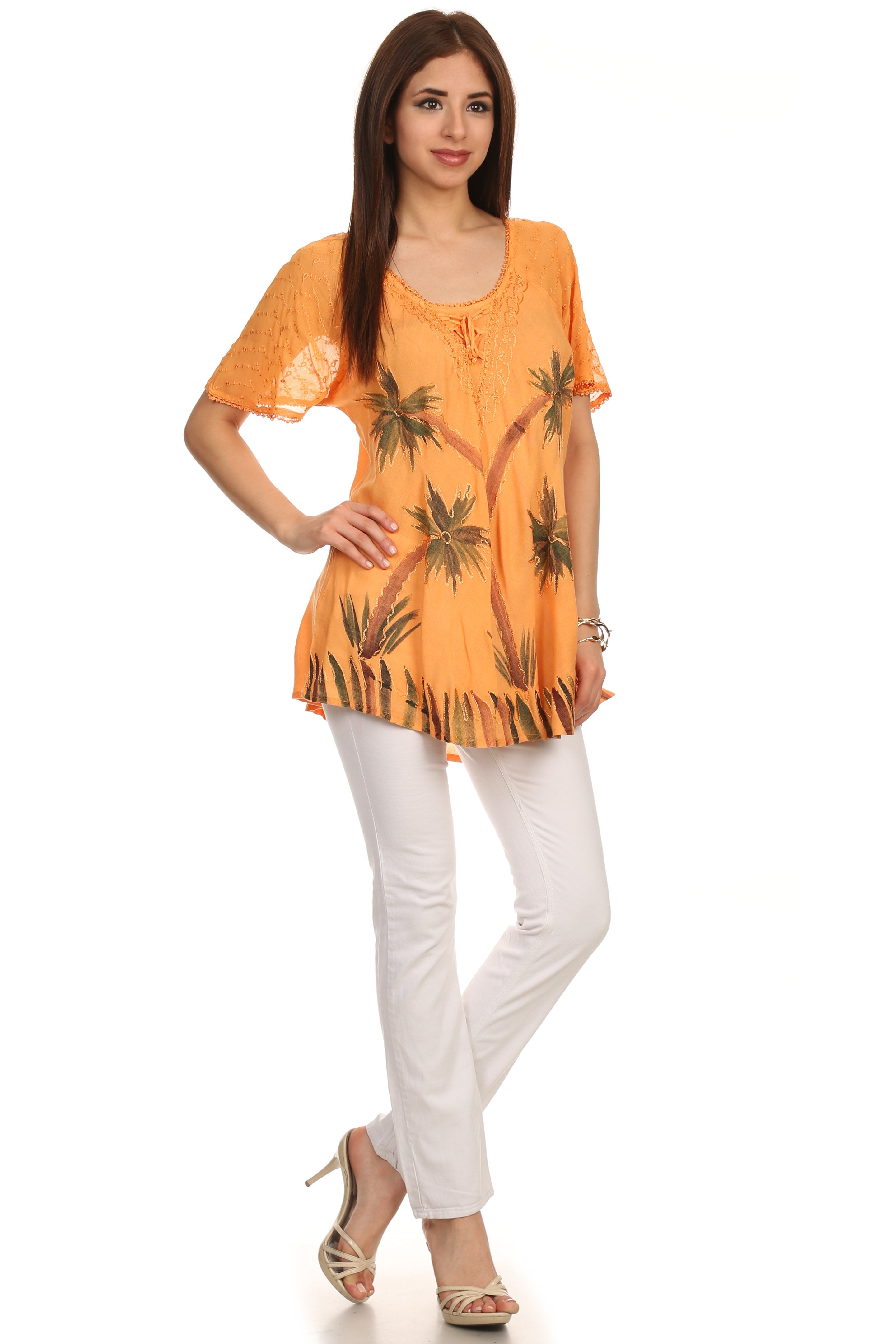 Woman wearing an orange floral top and white pants on a white background