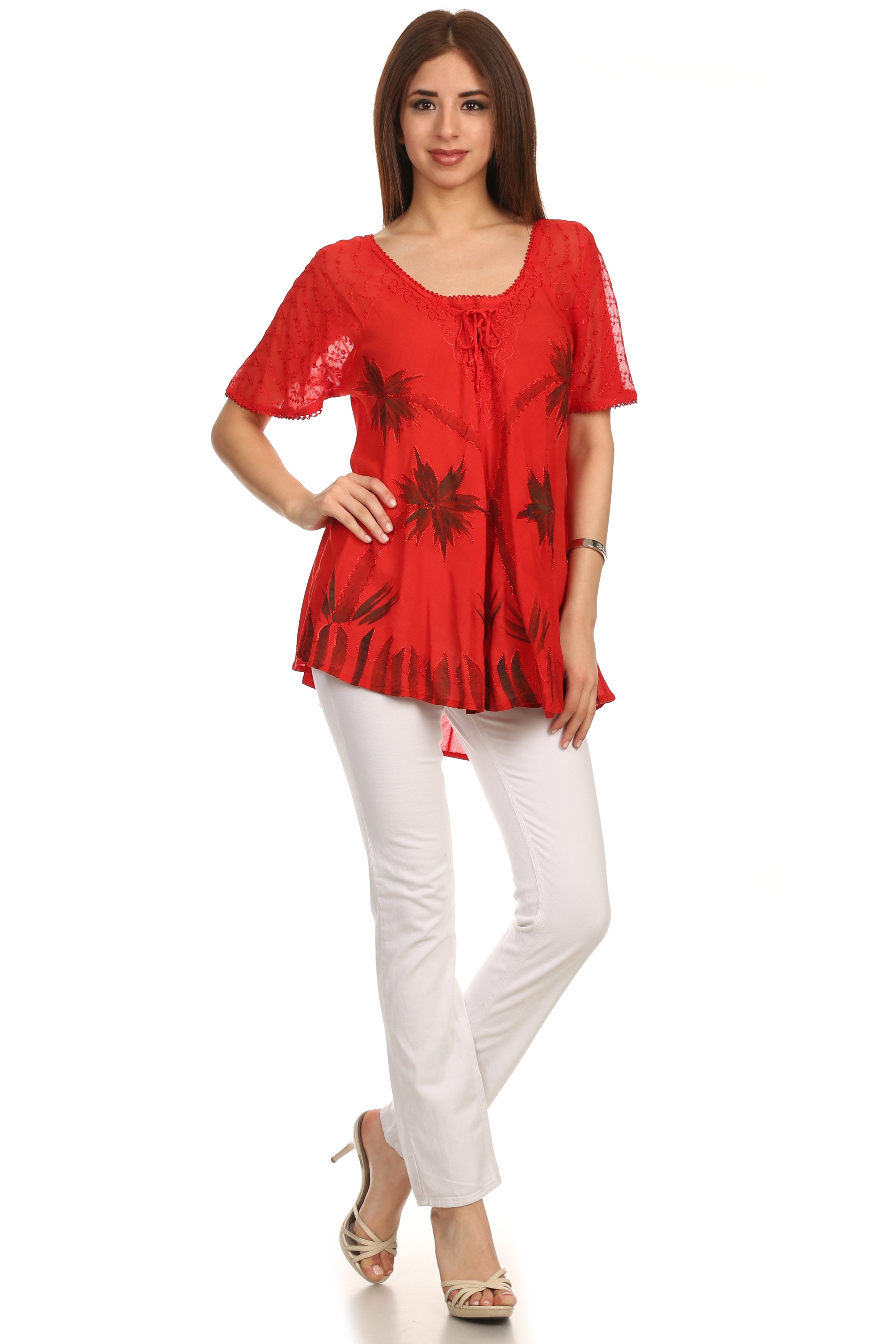 Woman wearing a red floral blouse and white pants on a white background