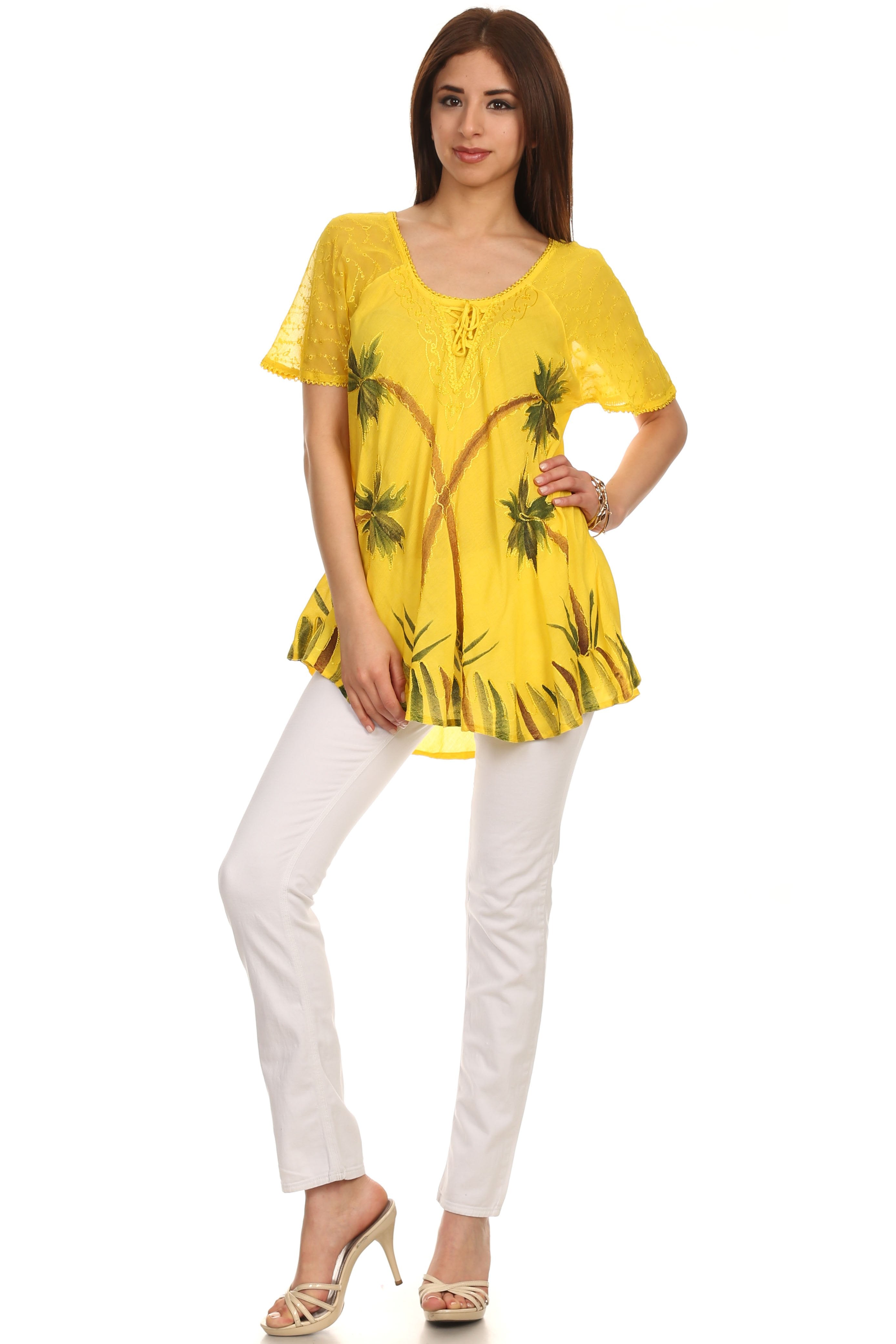 Woman wearing a yellow printed top and white pants on a white background