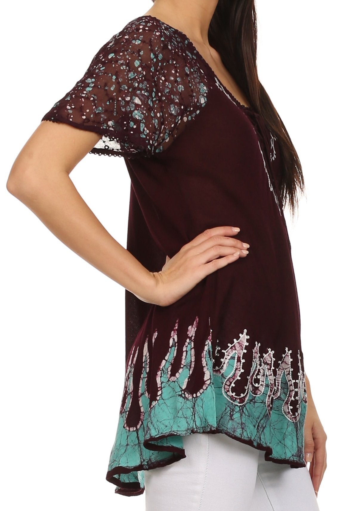 Woman wearing a burgundy and teal patterned top with white pants on a white background