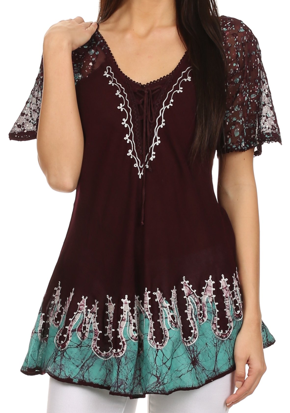 Woman wearing a dark brown and turquoise embroidered top with floral patterns.