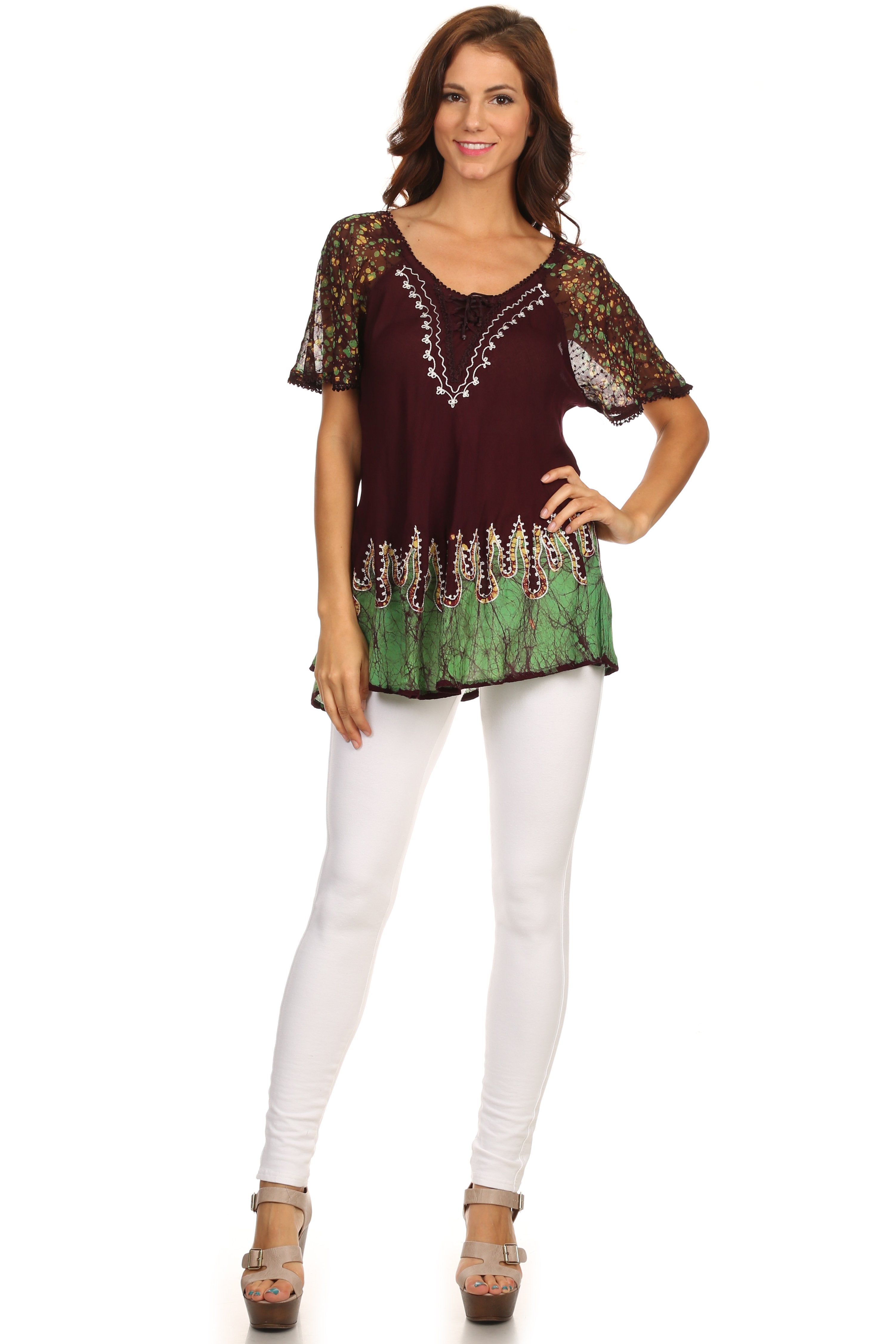 Woman wearing a patterned top and white pants on a white background