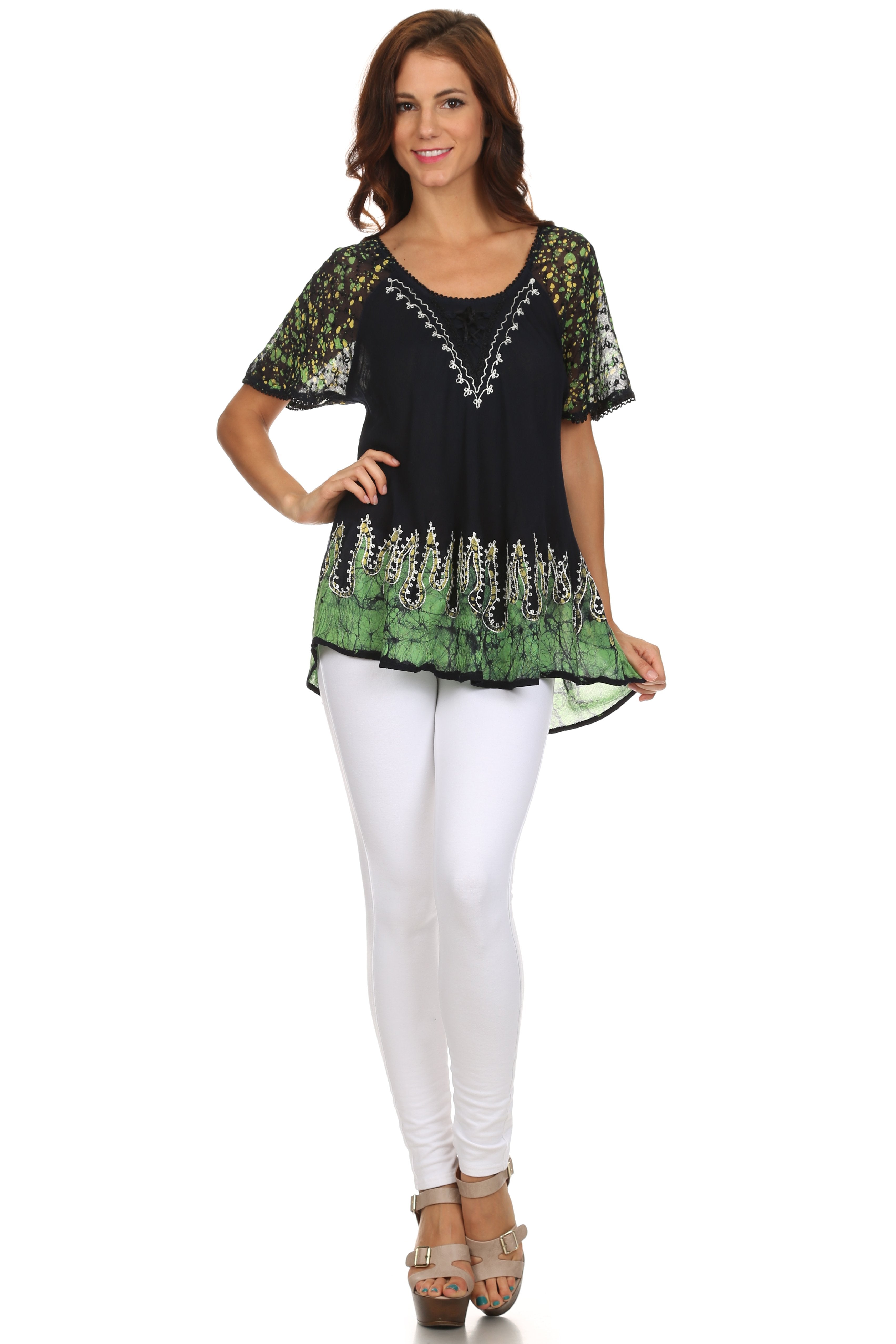 Woman wearing a black and green patterned top with white pants on a white background
