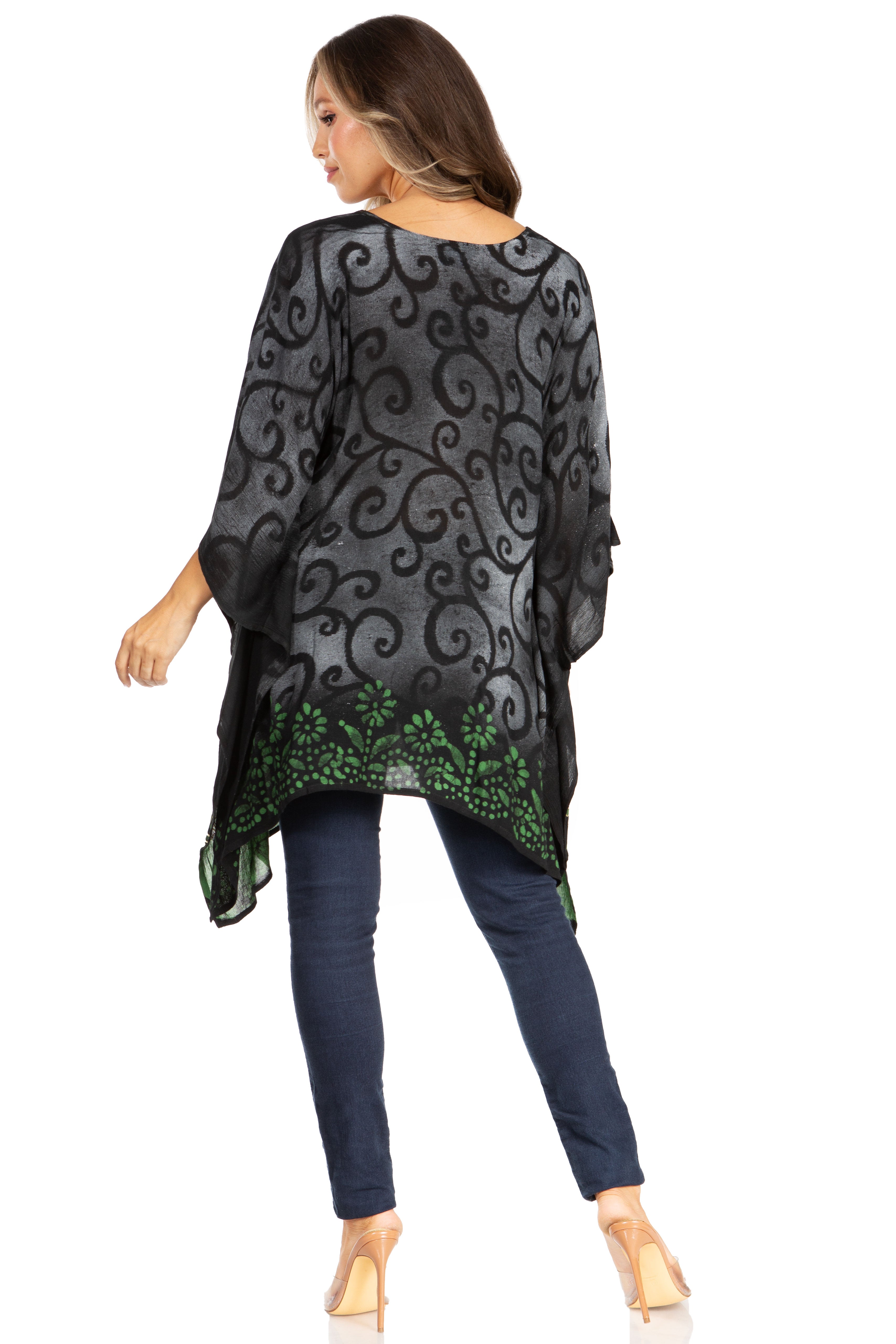 Woman wearing a black patterned top with green accents and dark pants on a white background