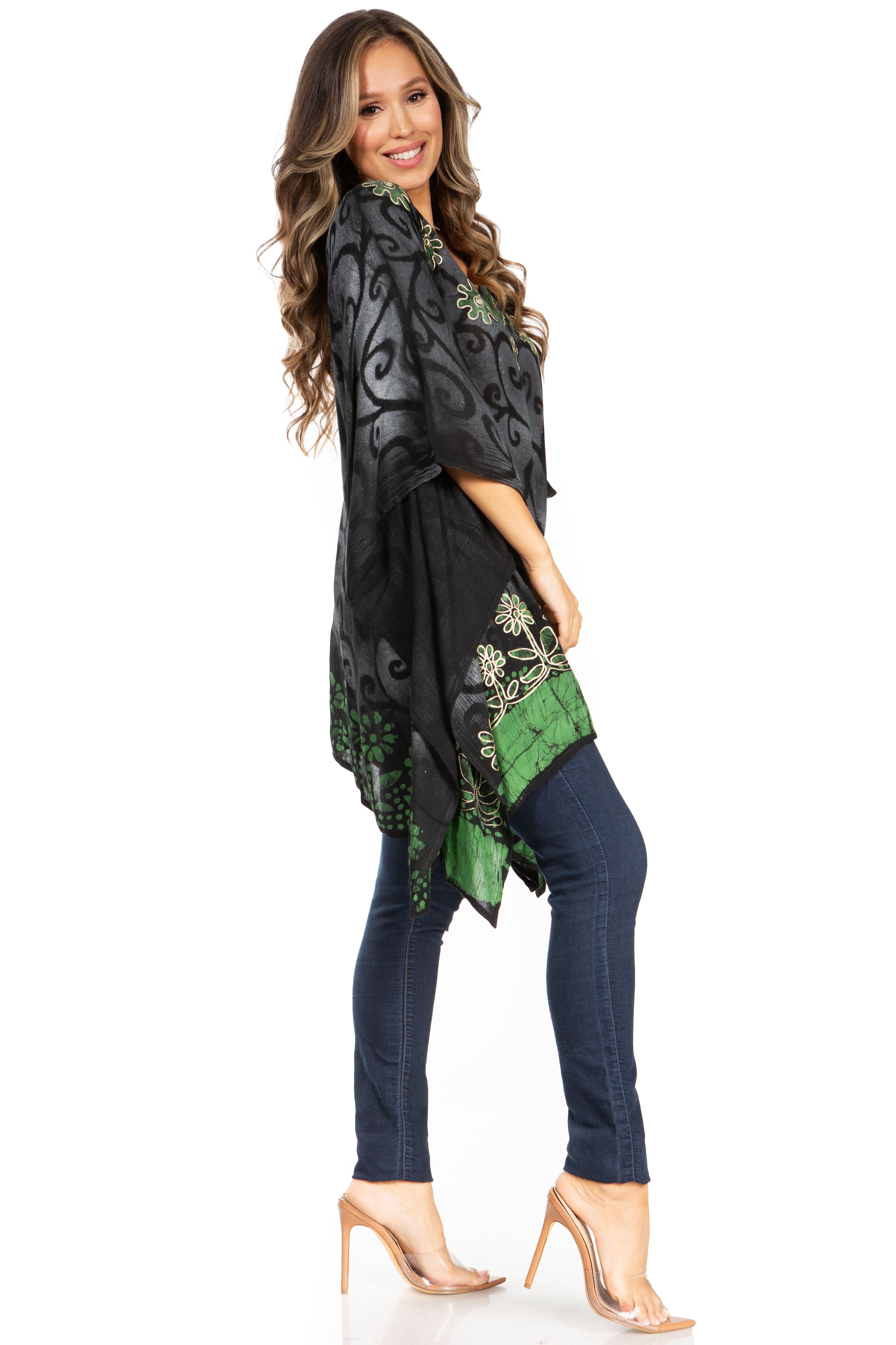Woman wearing a black and green patterned top with navy pants on a white background