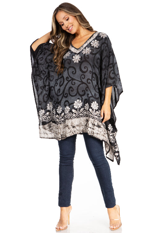 Woman wearing a black floral patterned poncho over a blue outfit on a white background