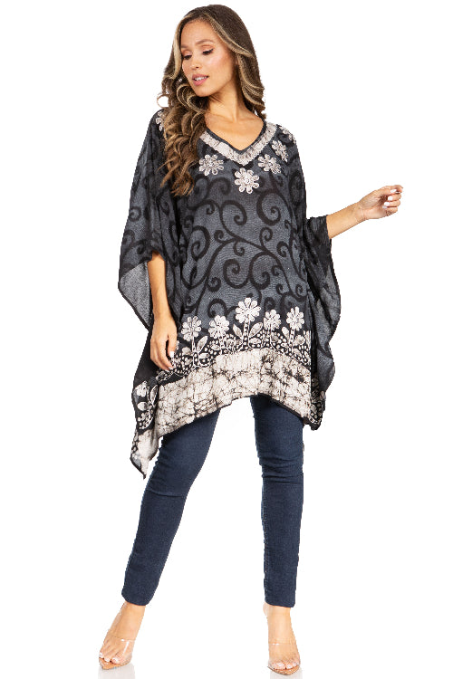 Woman wearing a black and white patterned poncho over a dark top and jeans on a white background