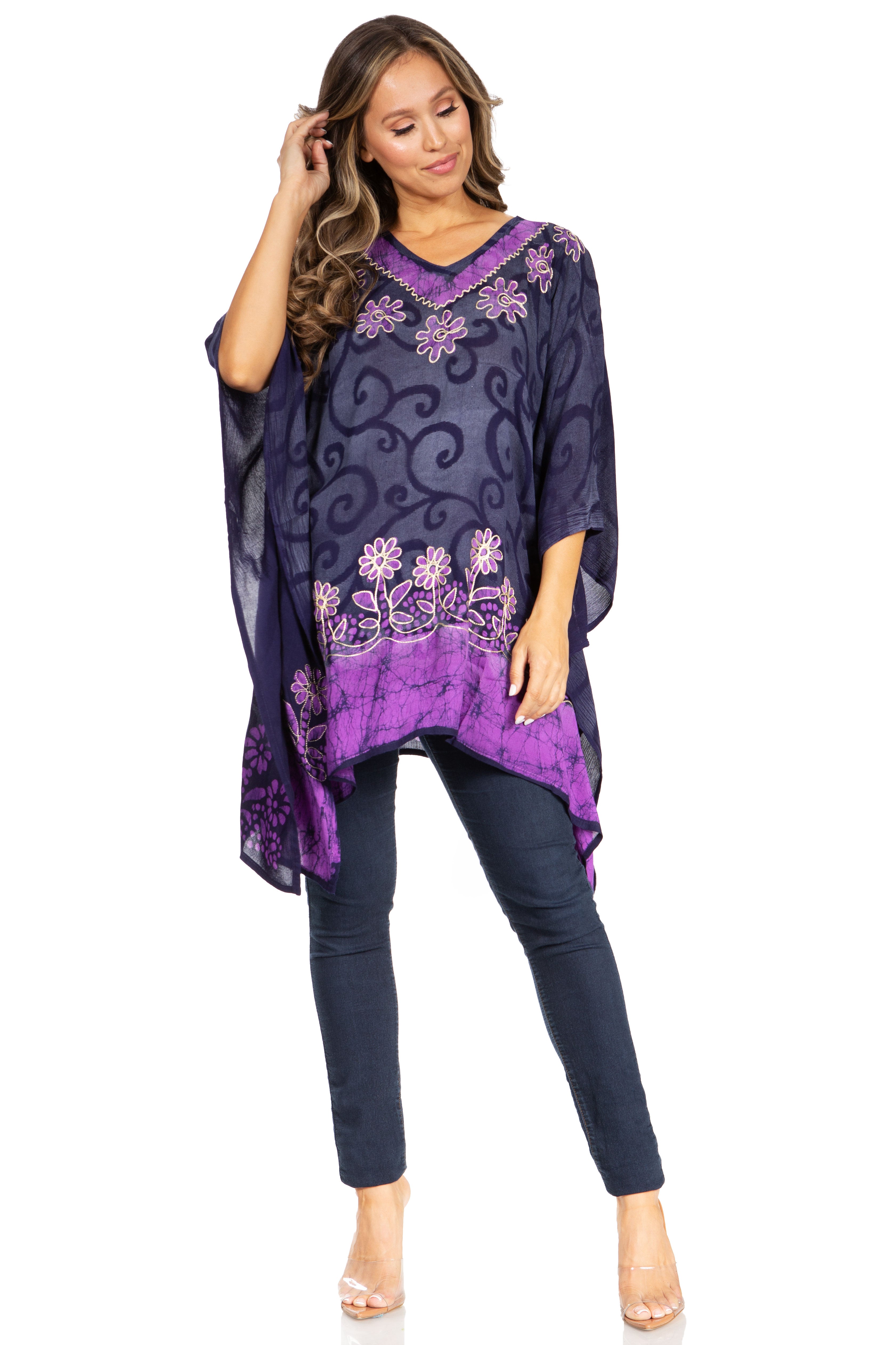 Woman wearing a purple patterned top and dark pants on a white background