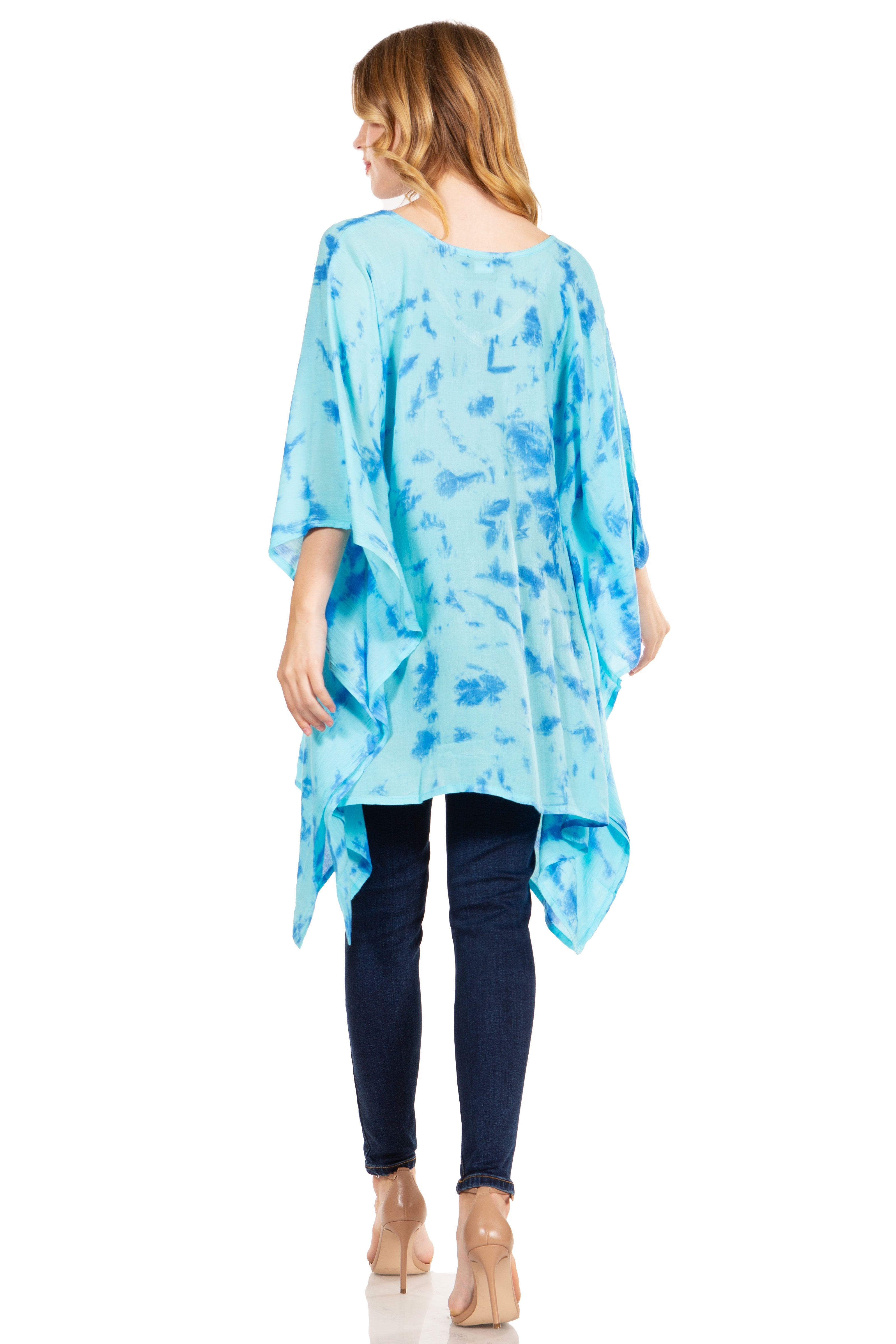 Woman wearing a blue patterned tunic over dark pants on a white background