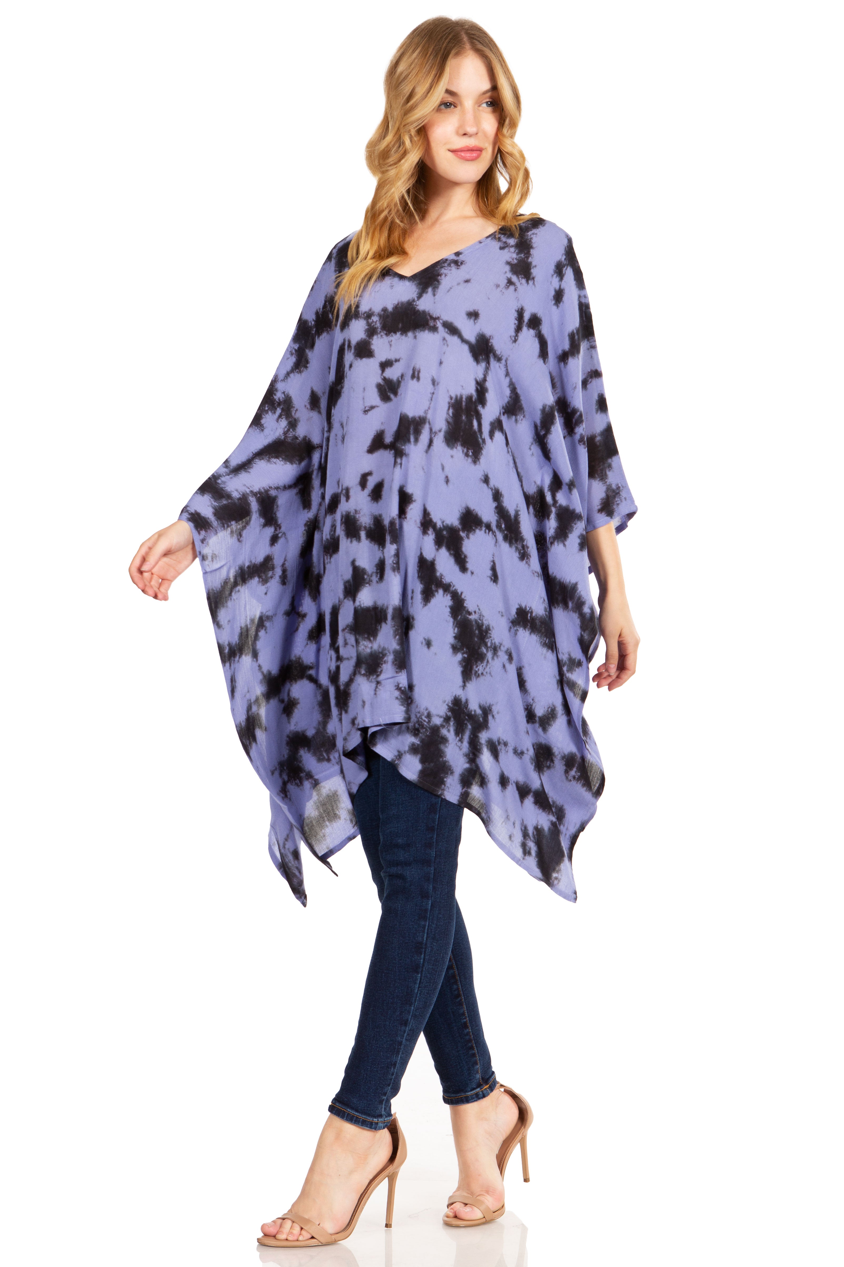 Woman wearing a blue tie-dye poncho and jeans on a white background