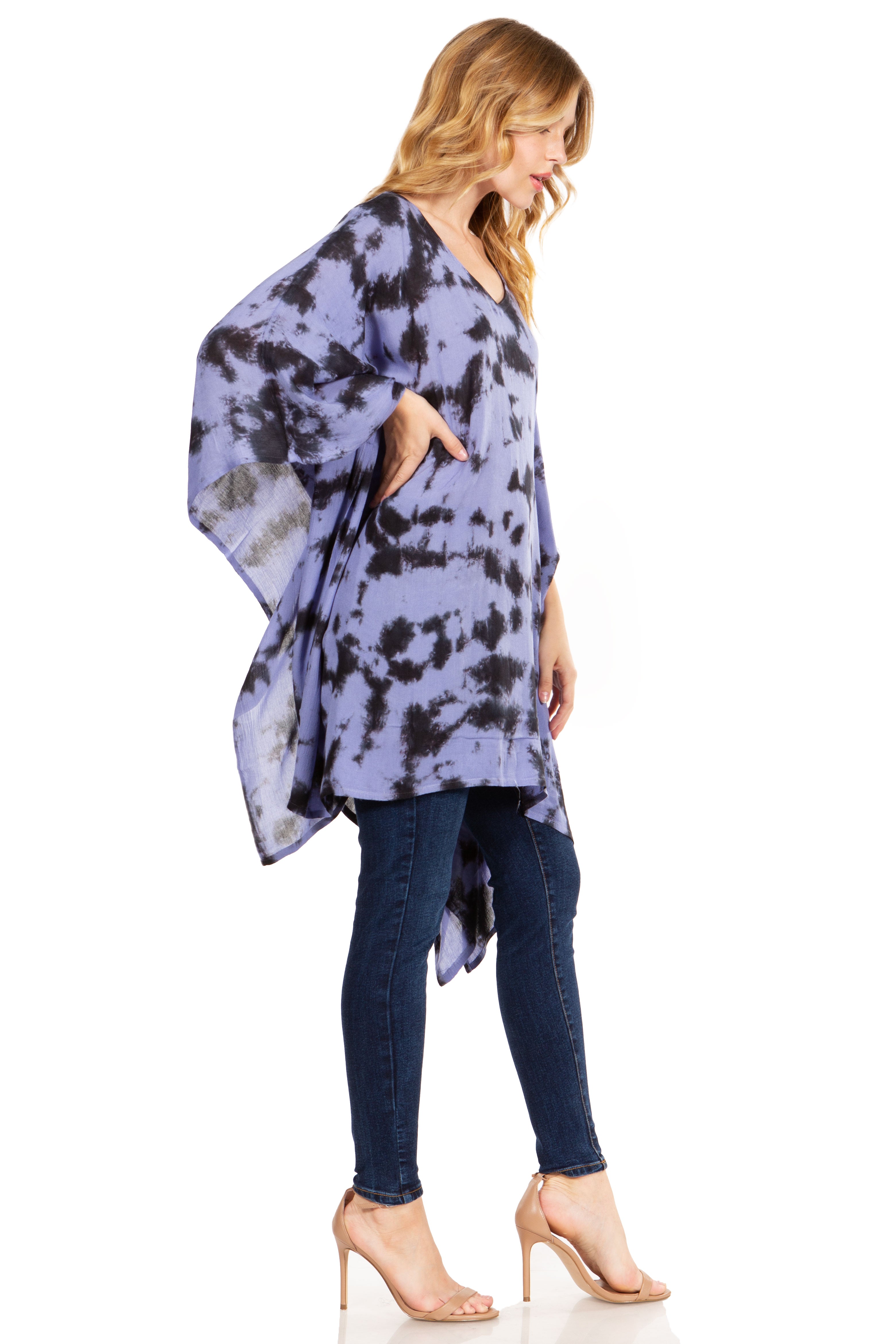 Woman wearing a tie-dye poncho and jeans on a white background