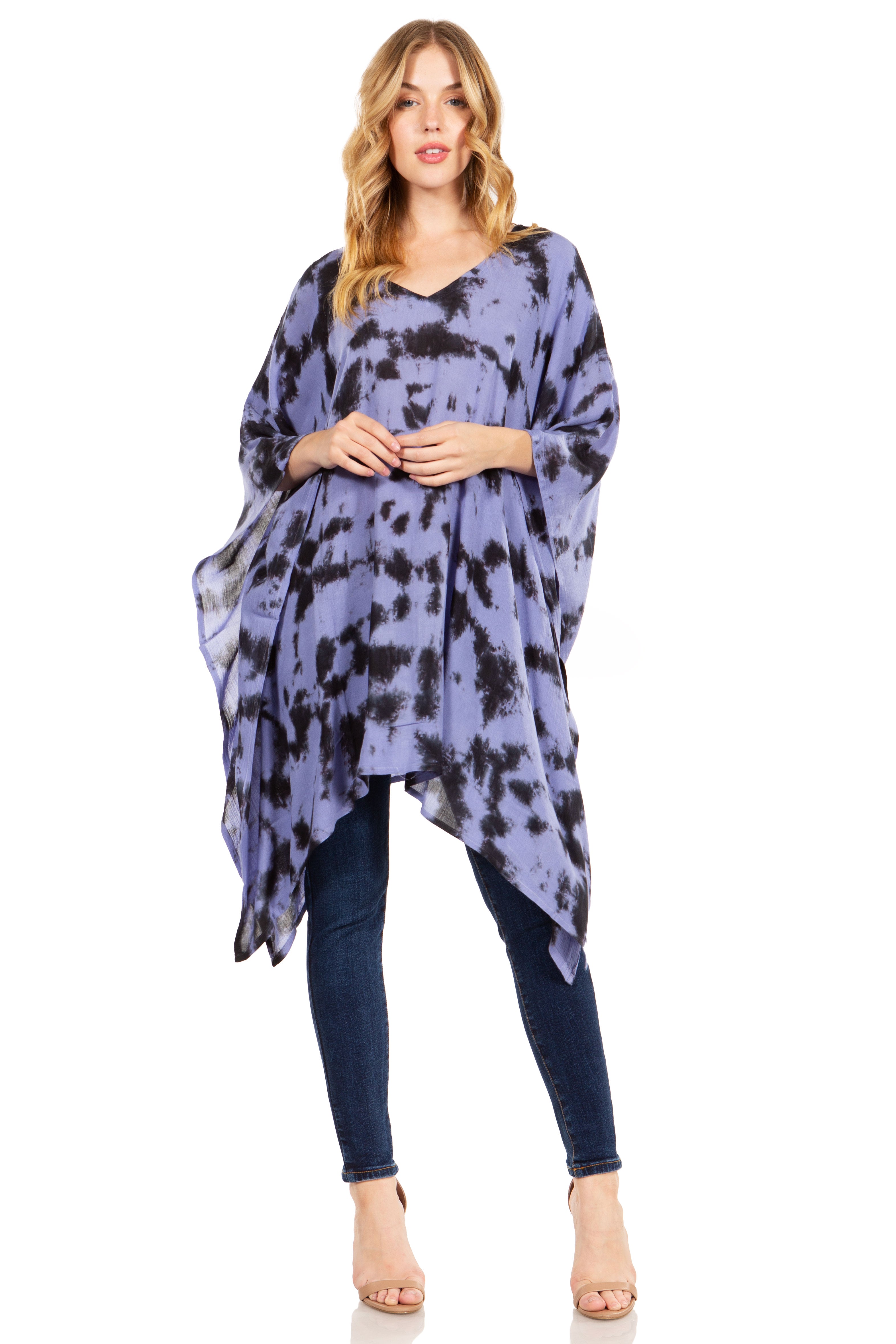 Woman wearing a tie-dye dress over a black top and jeans on a white background