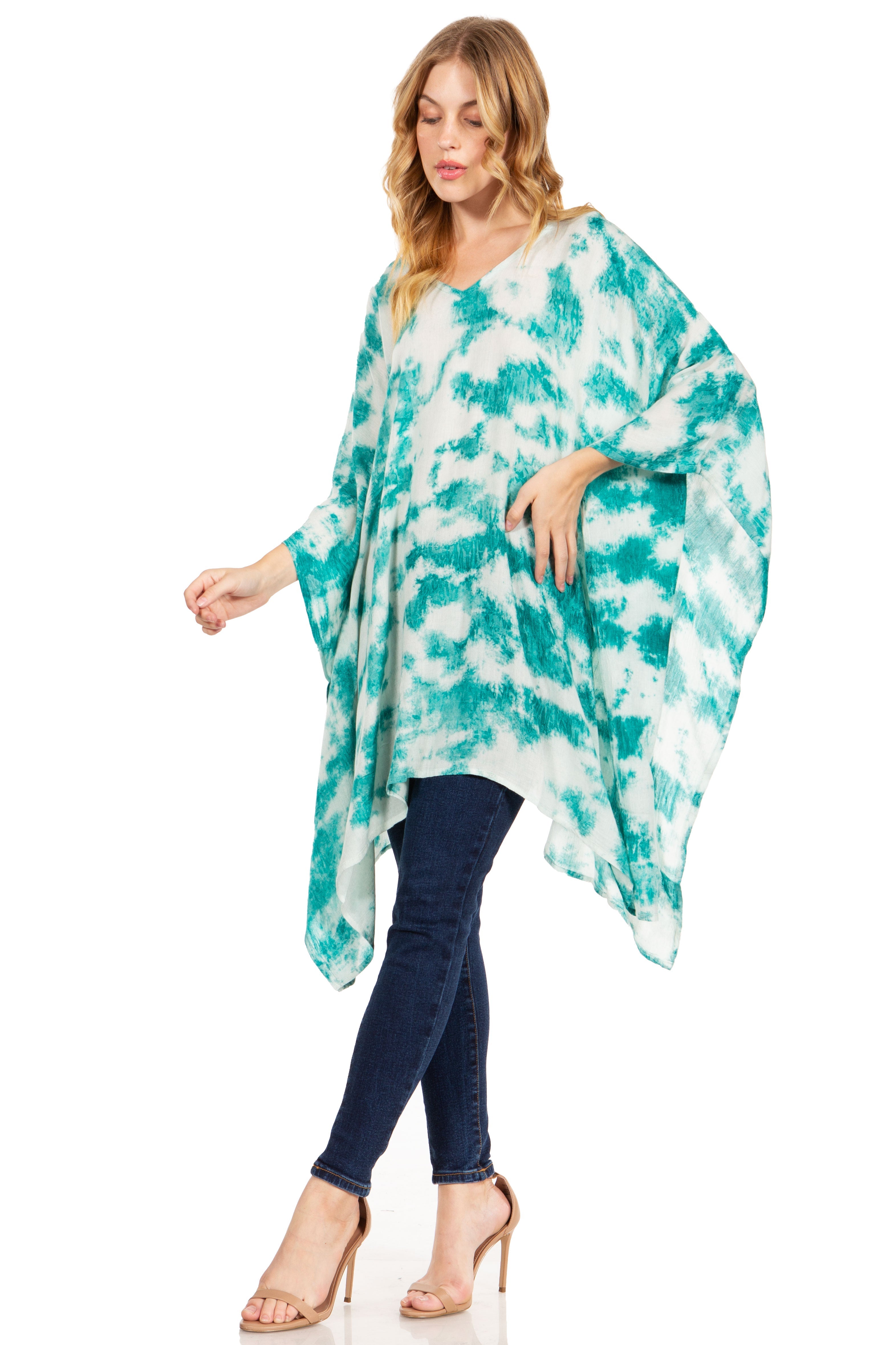 Woman wearing a turquoise and white tie-dye poncho over a blue outfit on a white background