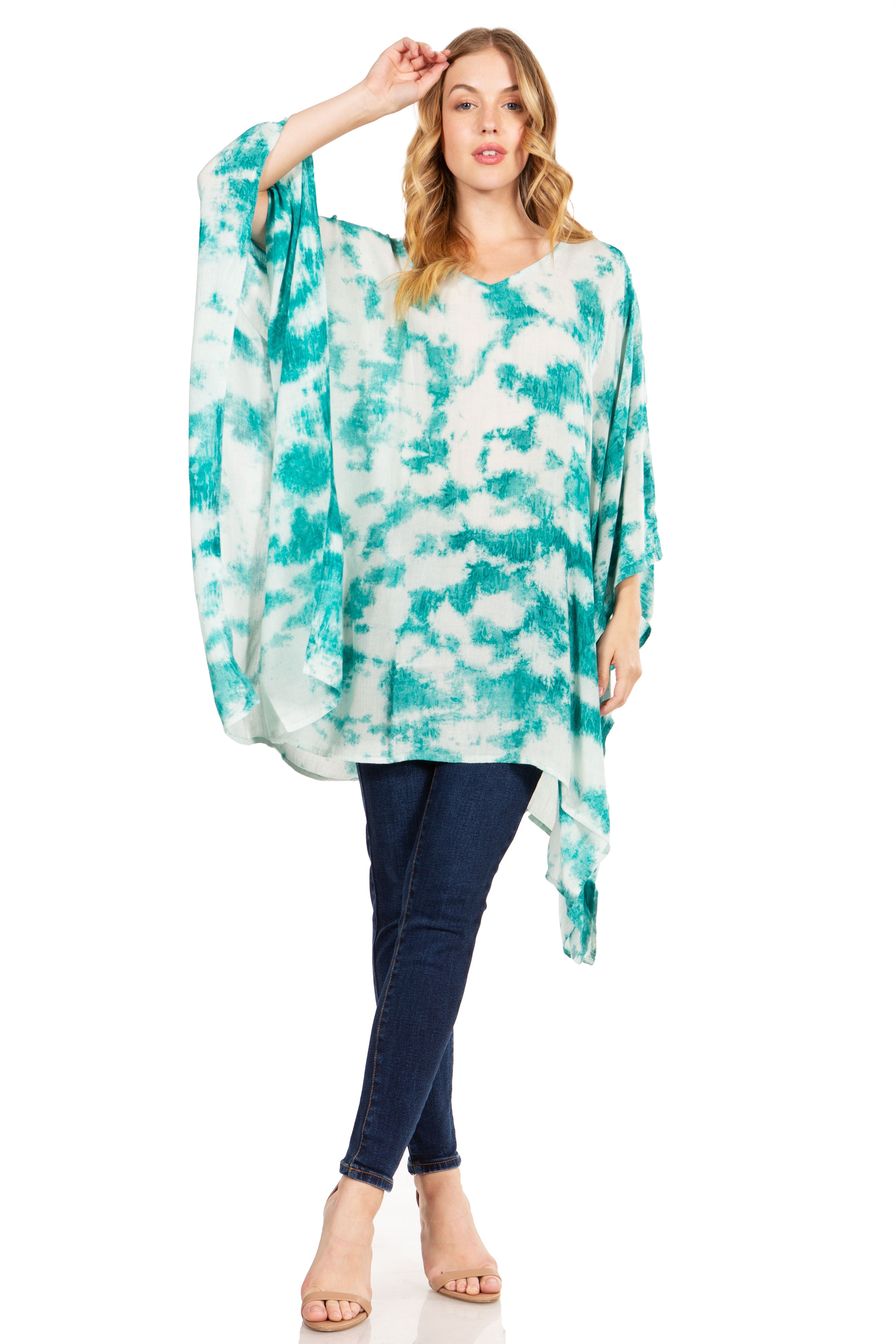 Woman wearing a turquoise and white tie-dye poncho with blue pants on a white background