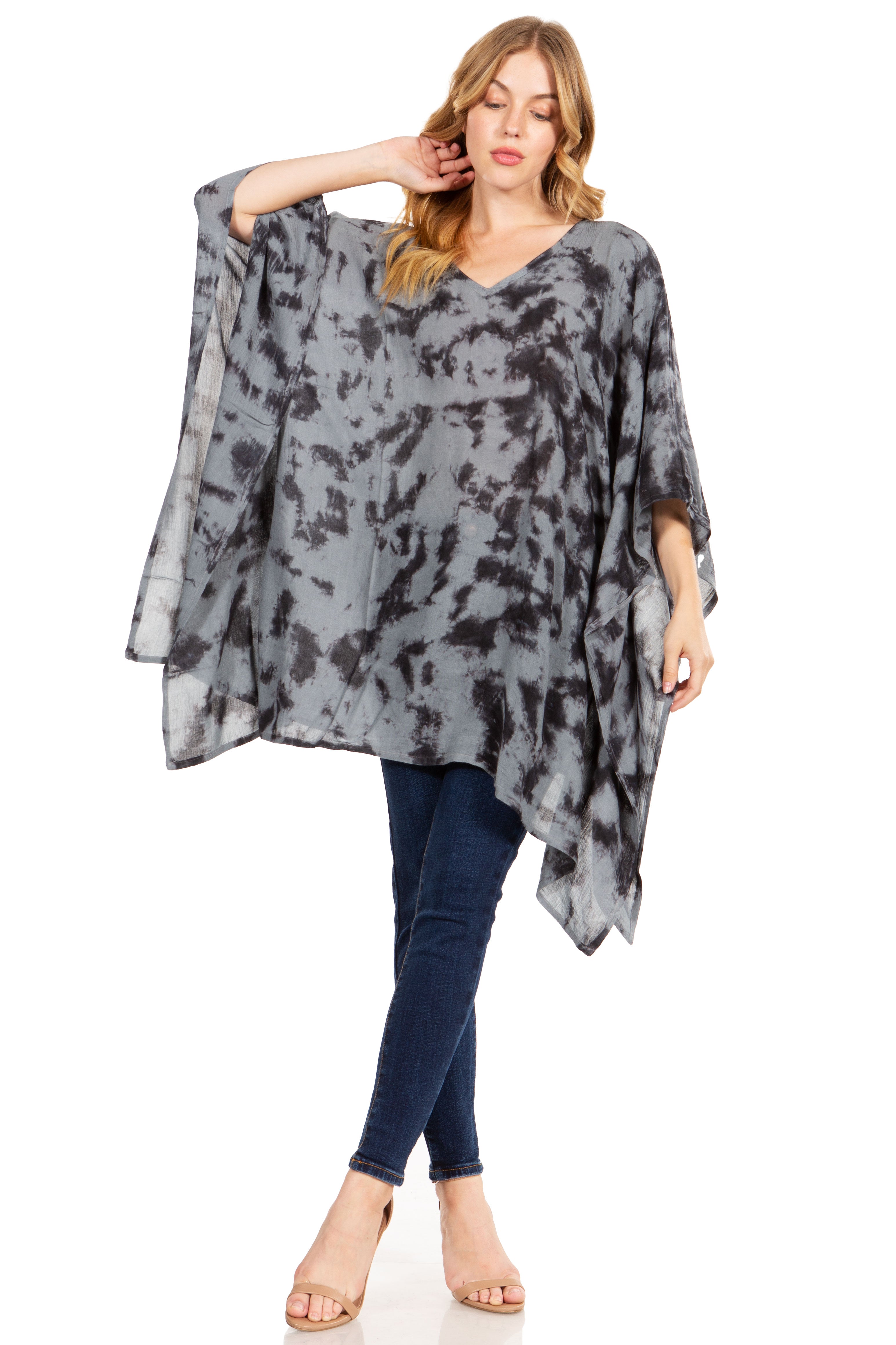 Woman wearing a gray patterned poncho over a blue outfit on a white background