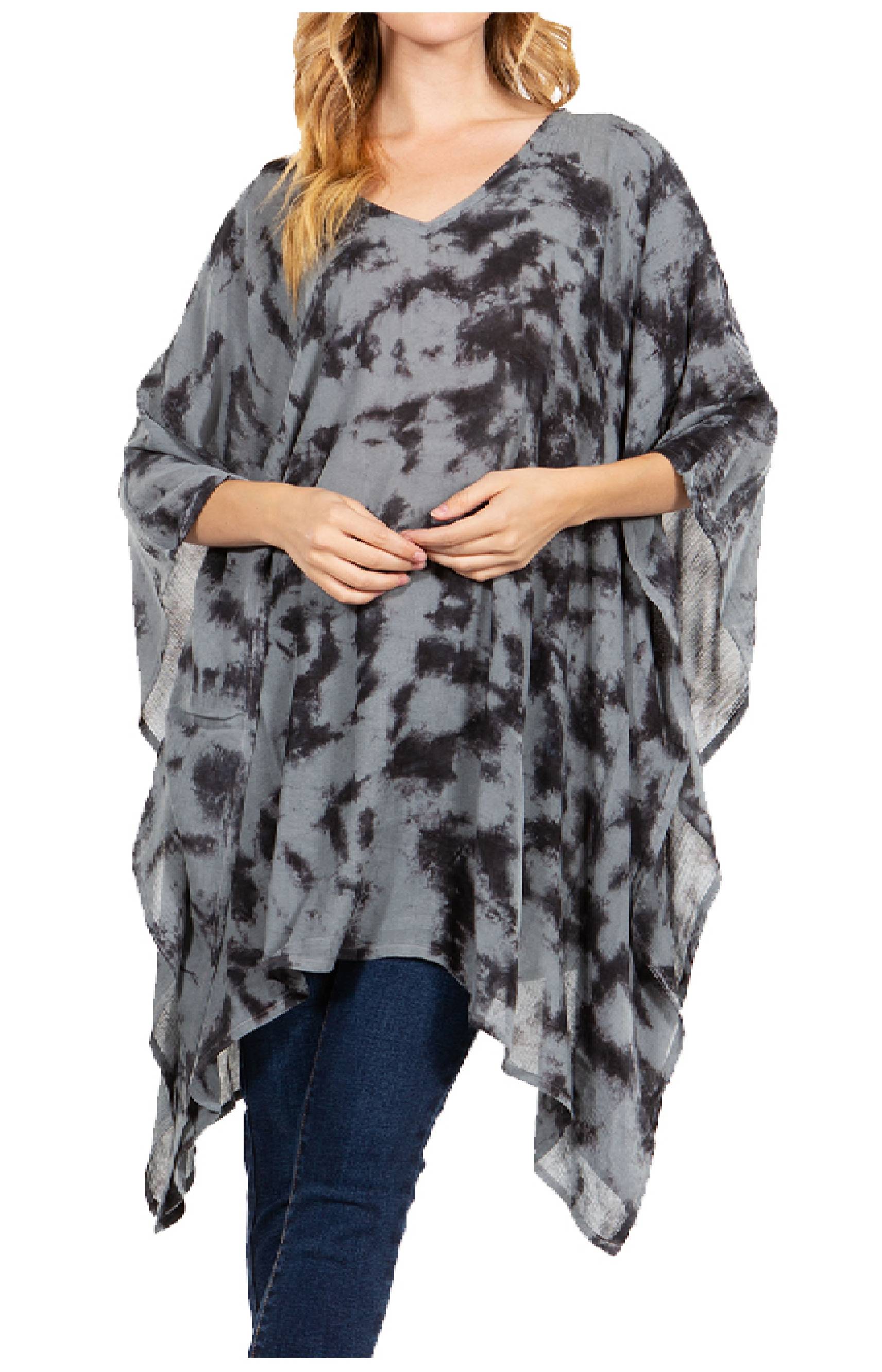 Woman wearing a gray tie-dye poncho over blue jeans on a white background