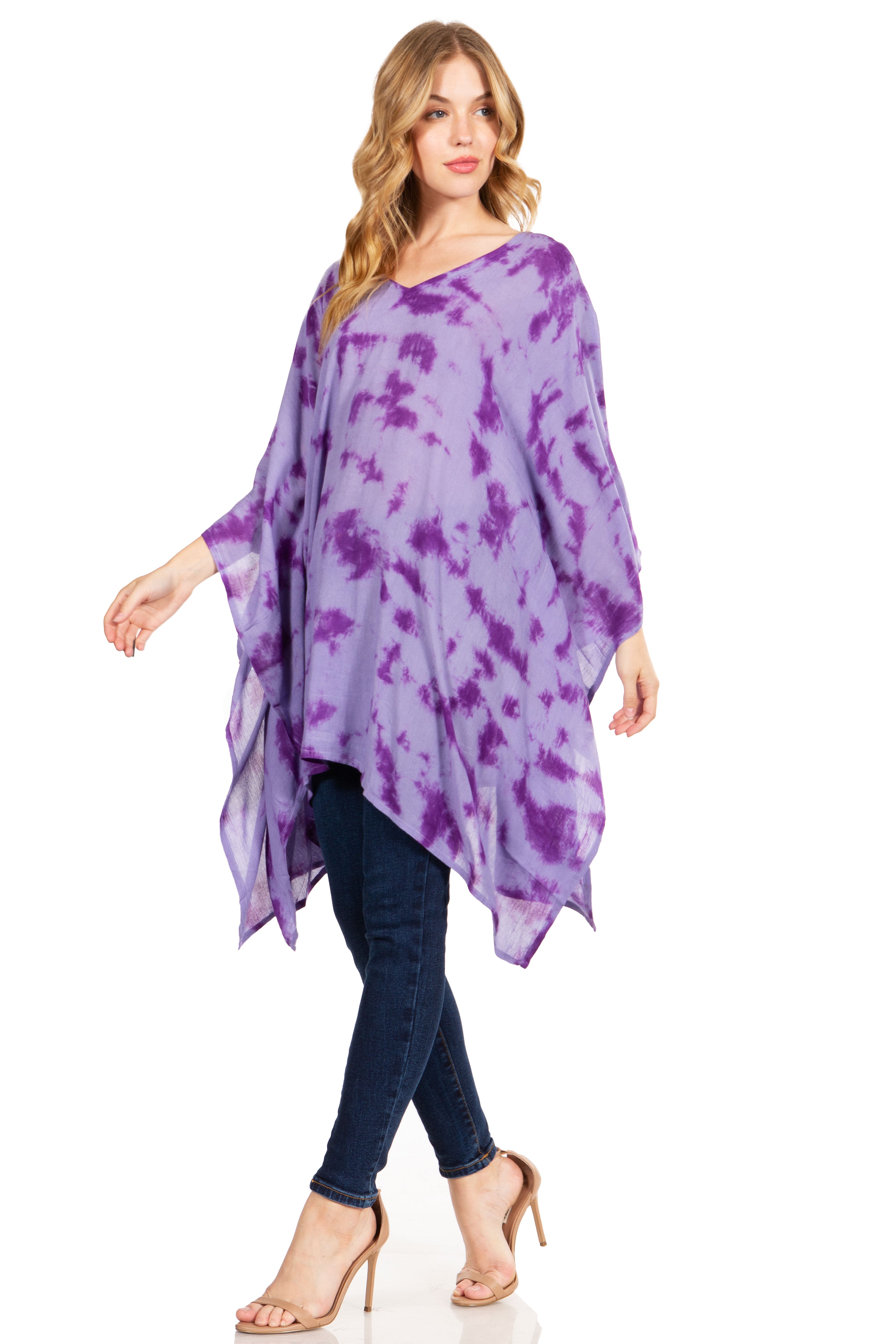 Woman wearing a purple tie-dye poncho over a black top and jeans on a white background