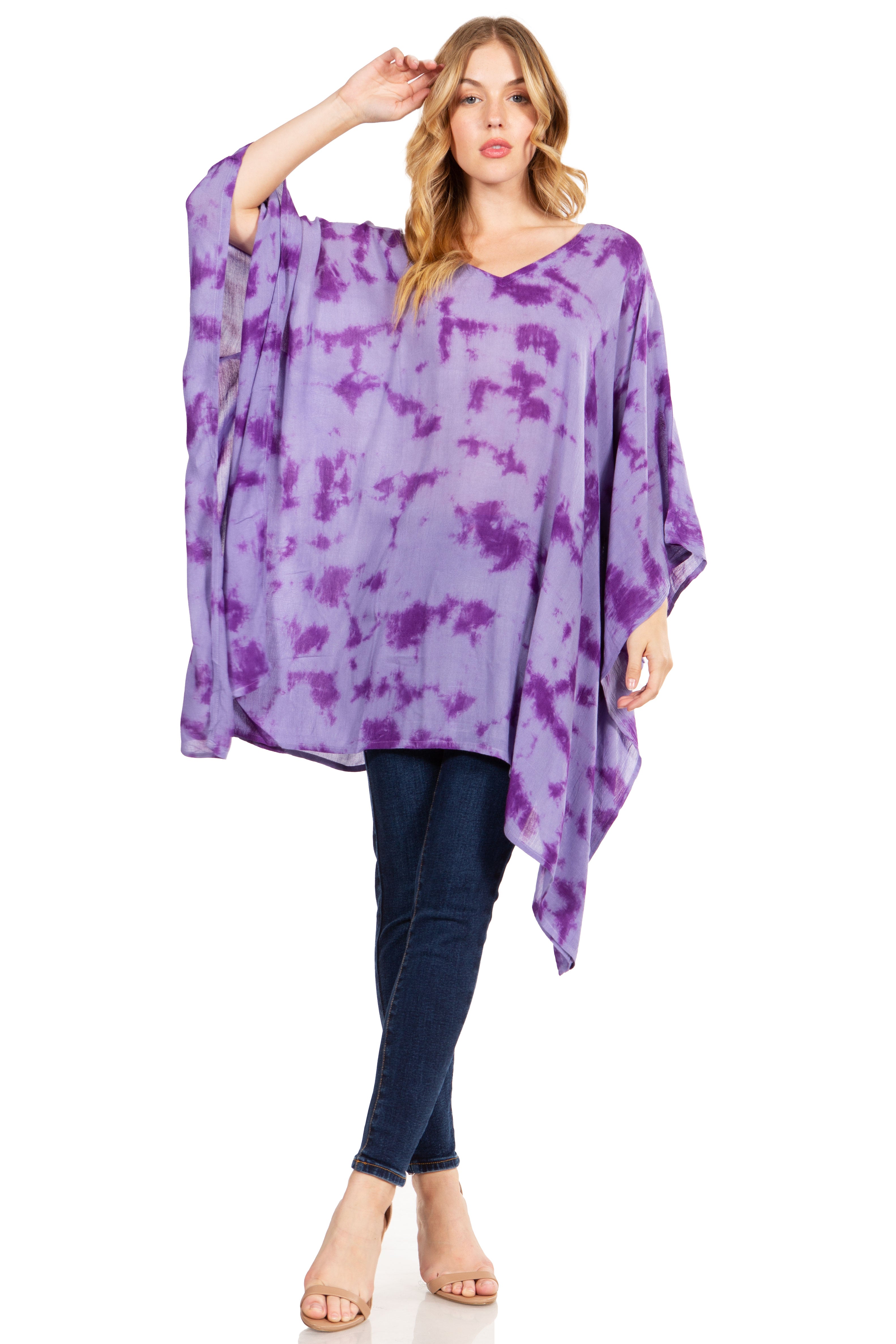 Woman wearing a purple tie-dye poncho and dark jeans on a white background