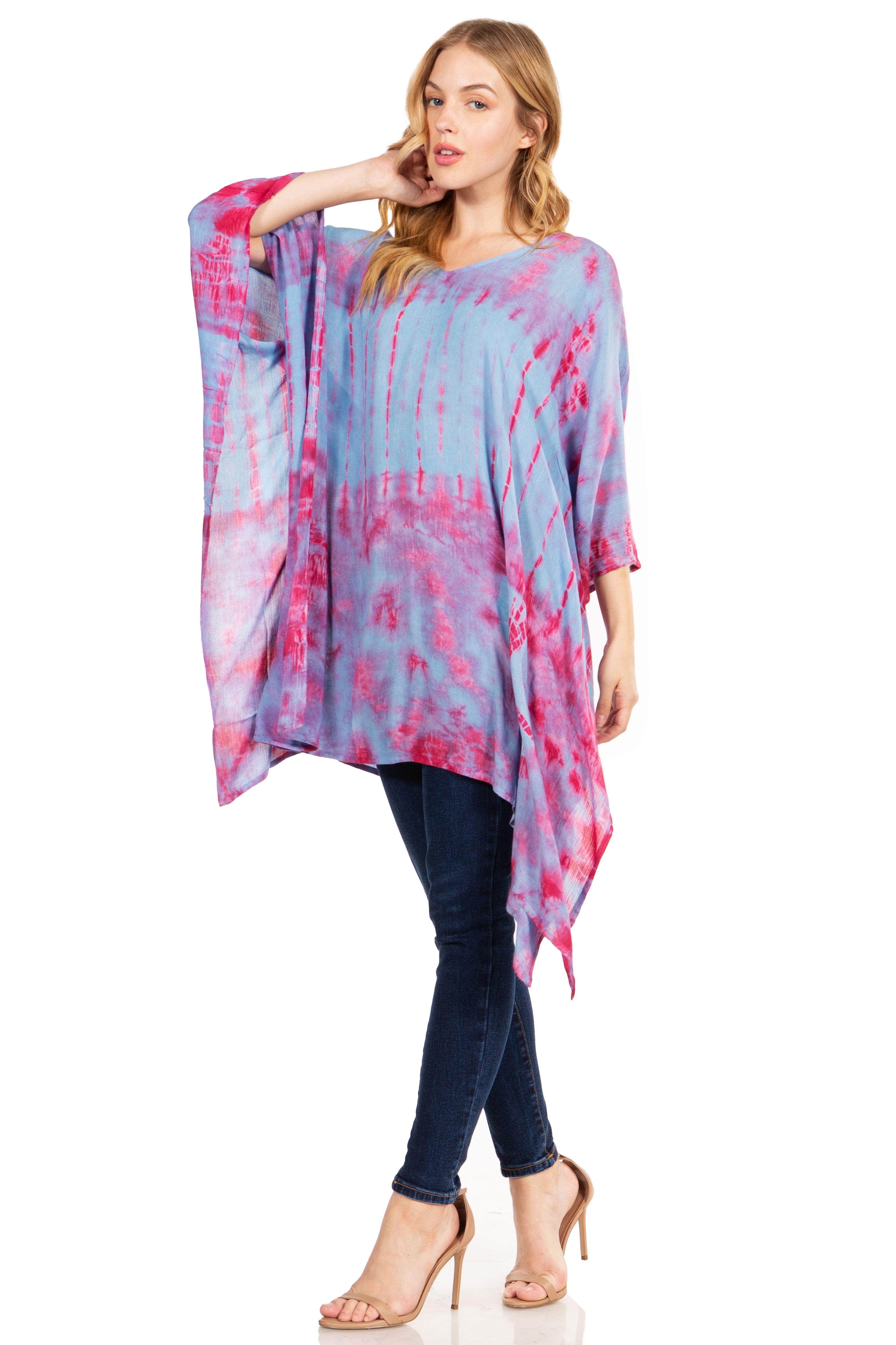 Woman wearing a colorful tie-dye top and dark jeans on a white background