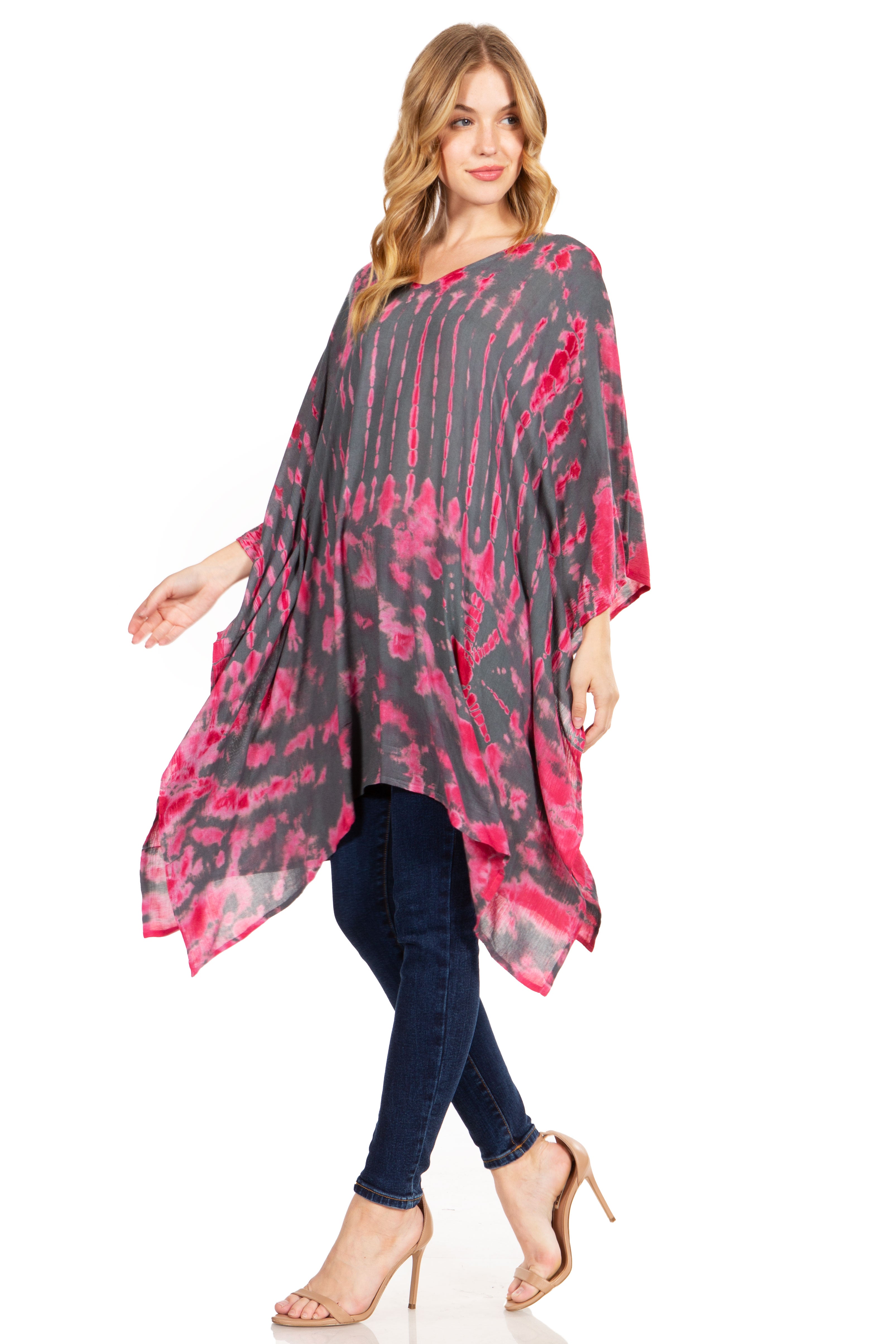 Woman wearing a pink and gray tie-dye poncho with blue jeans on a white background