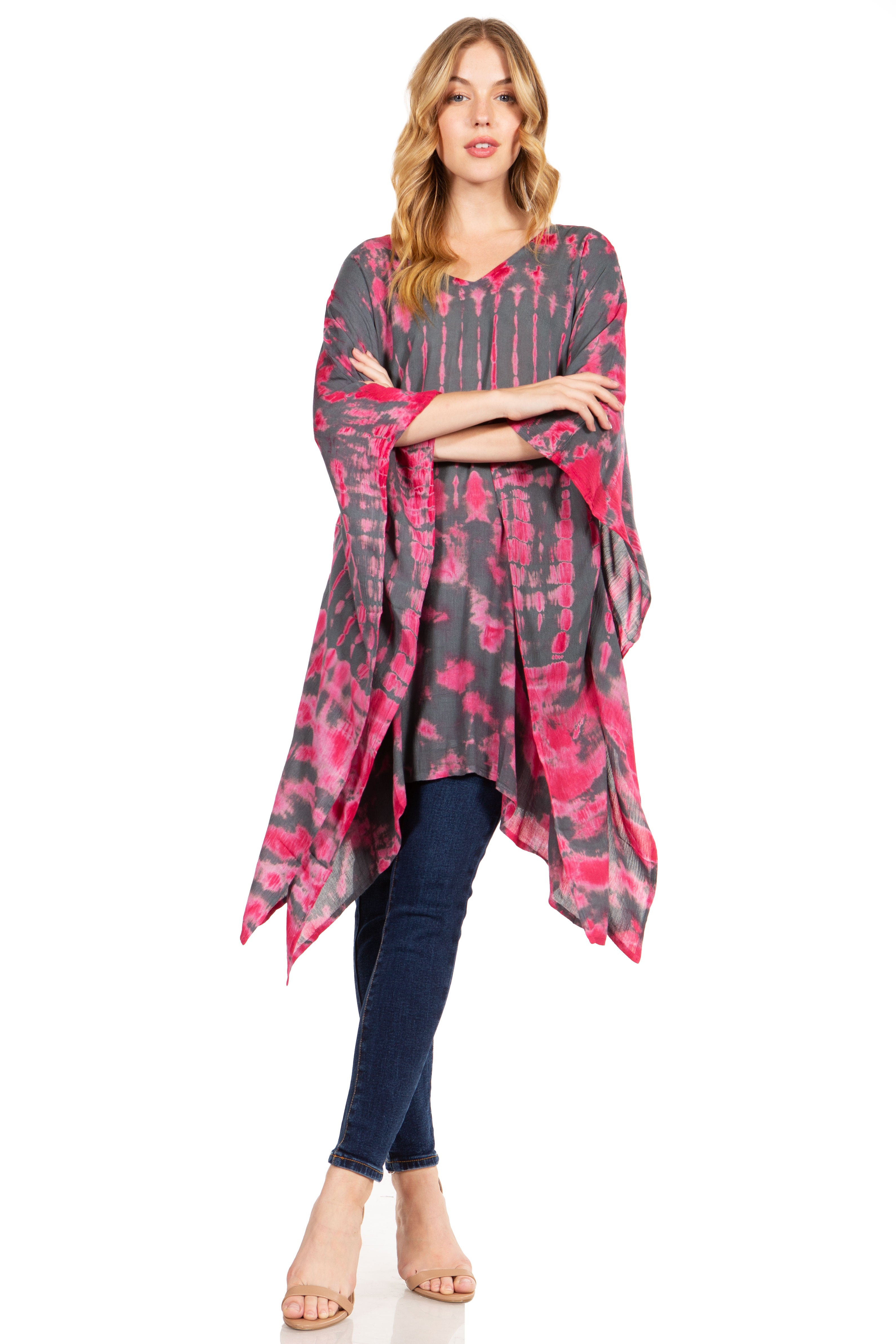 Woman wearing a pink and gray patterned tunic over blue jeans on a white background