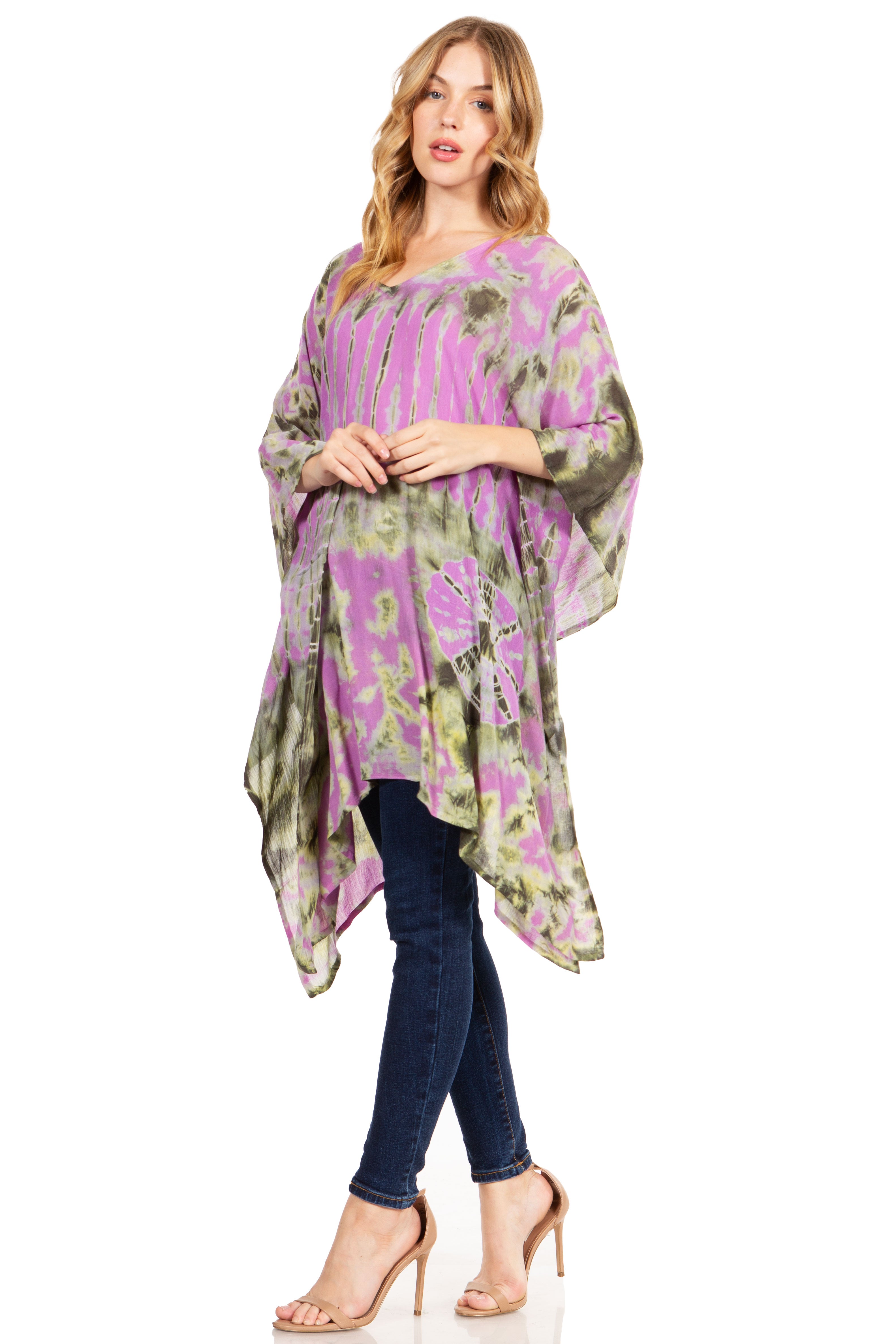 Woman wearing a purple and green patterned dress over a black top with blue jeans on a white background