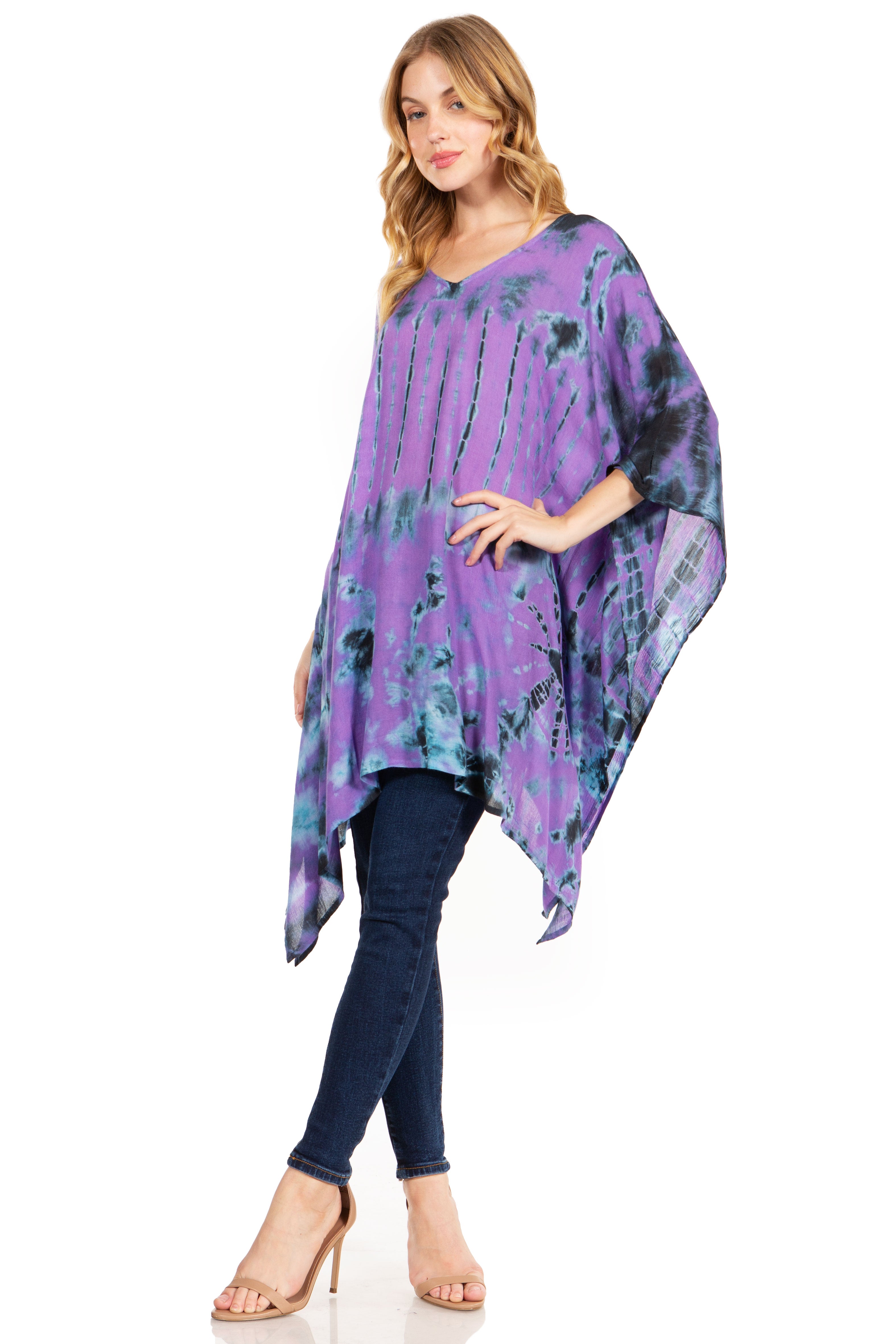 Woman wearing a purple tie-dye poncho over a blue top and jeans on a white background