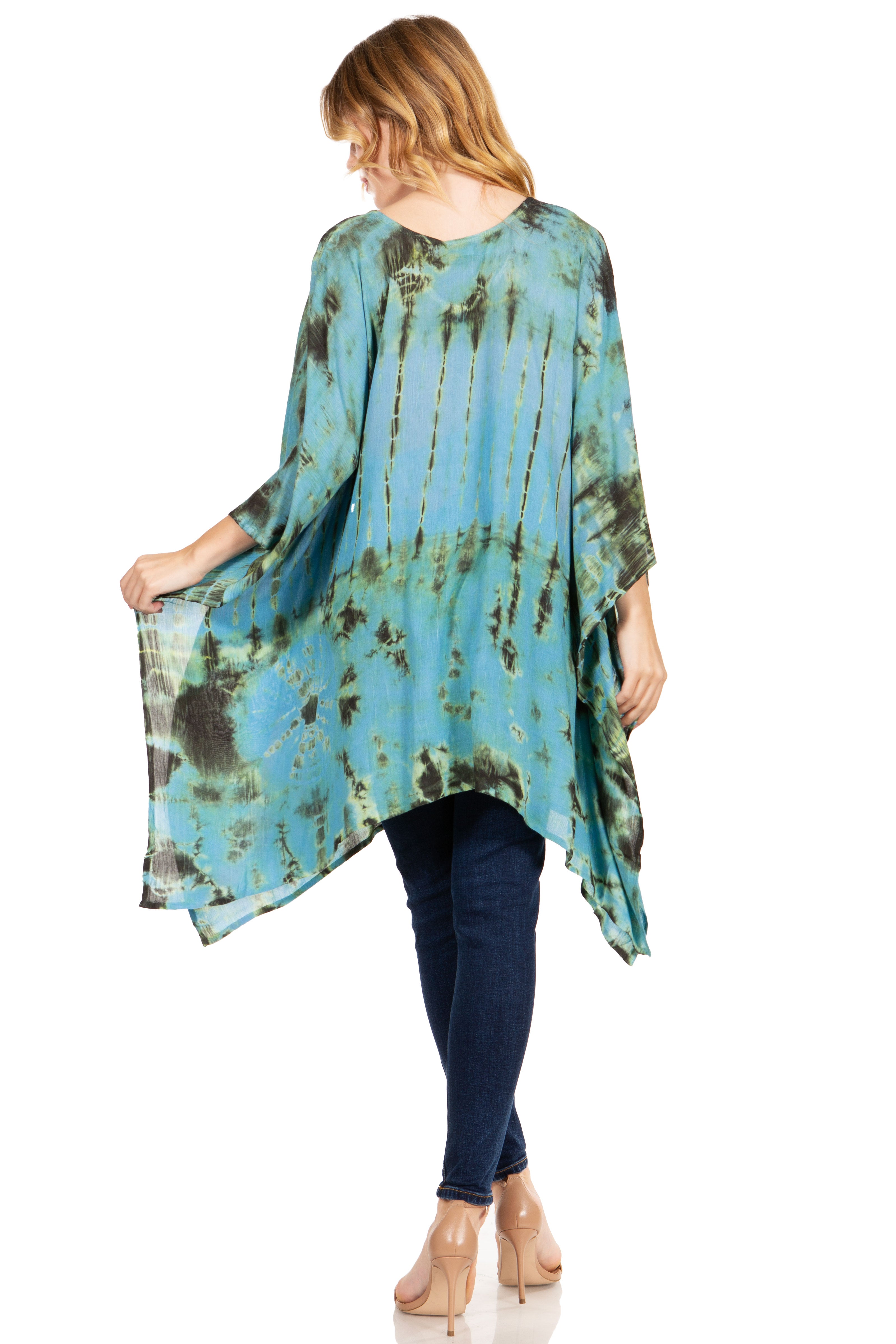 Woman wearing a tie-dye kimono-style top and dark jeans on a white background