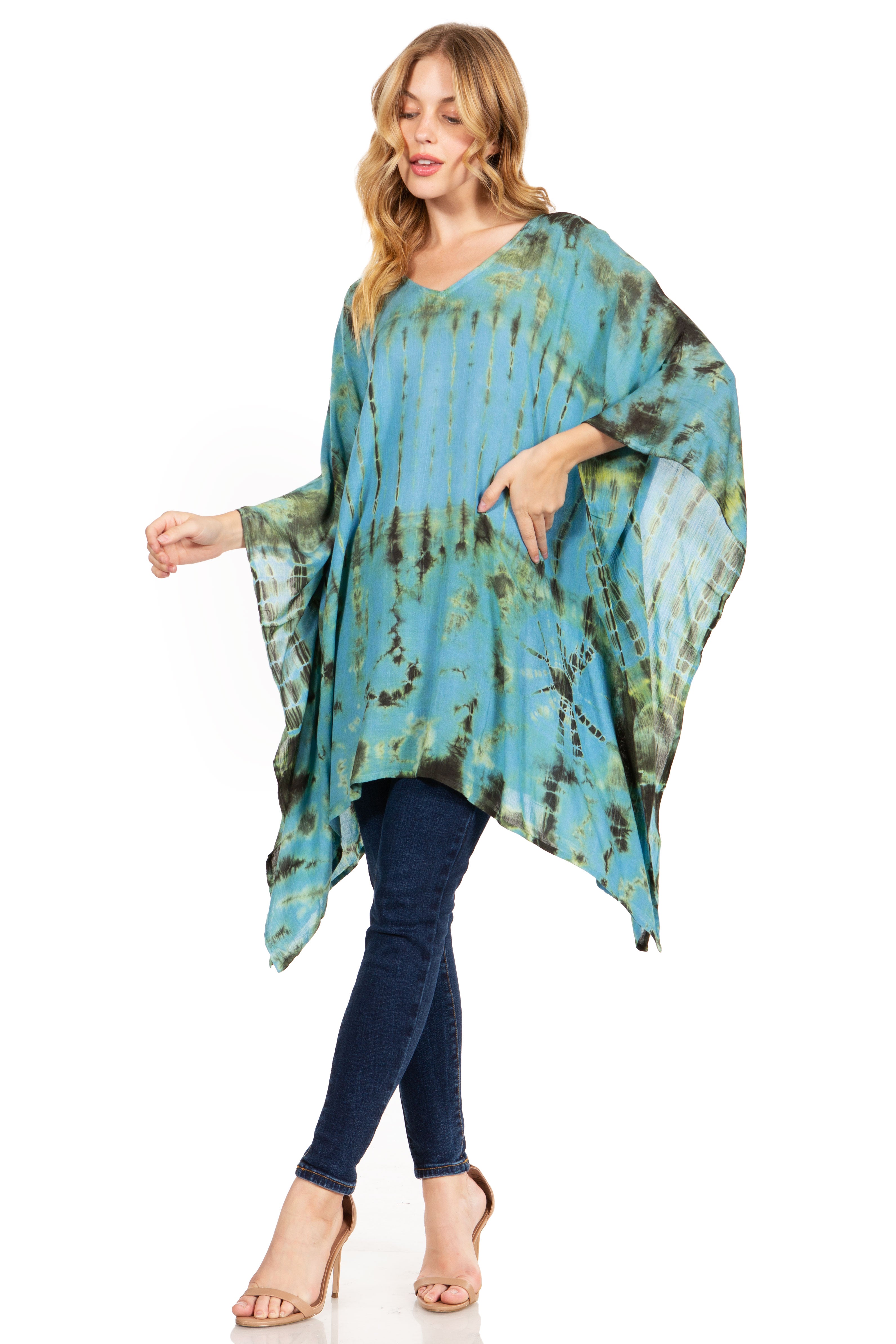 Woman wearing a tie-dye poncho over a blue top and jeans on a white background