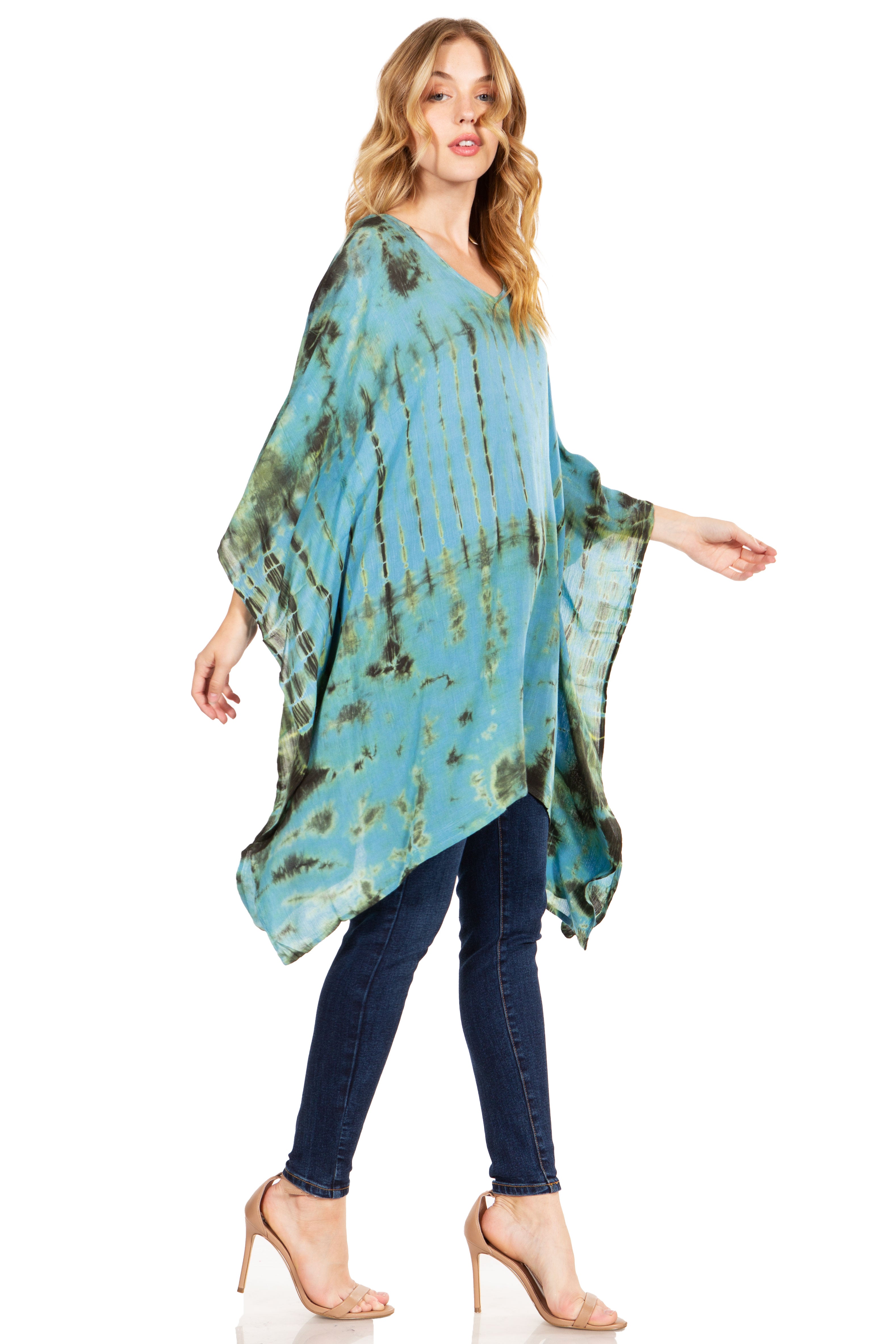 Woman wearing a blue tie-dye poncho over a black top and jeans on a white background