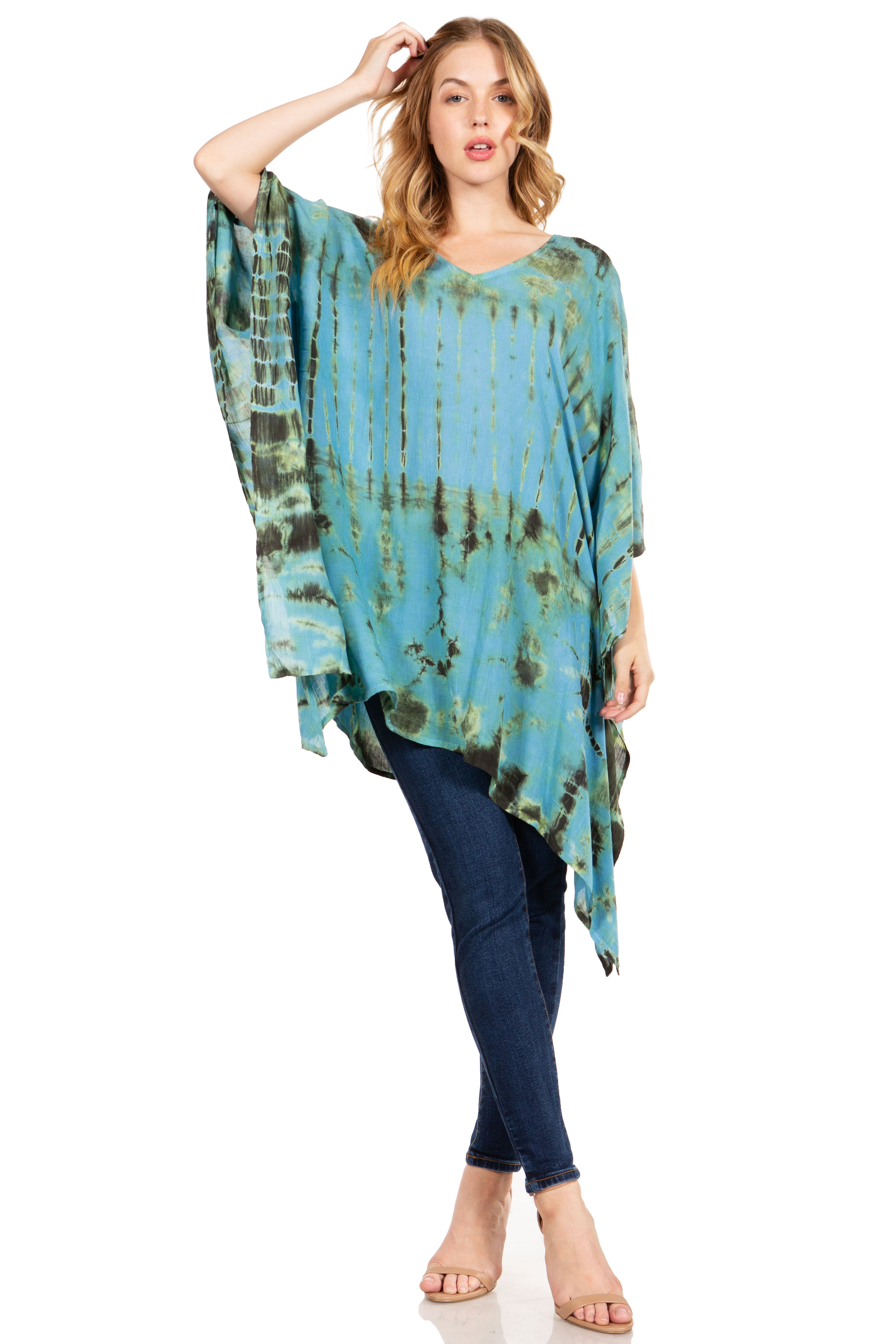 Woman wearing a blue tie-dye poncho over dark pants on a white background