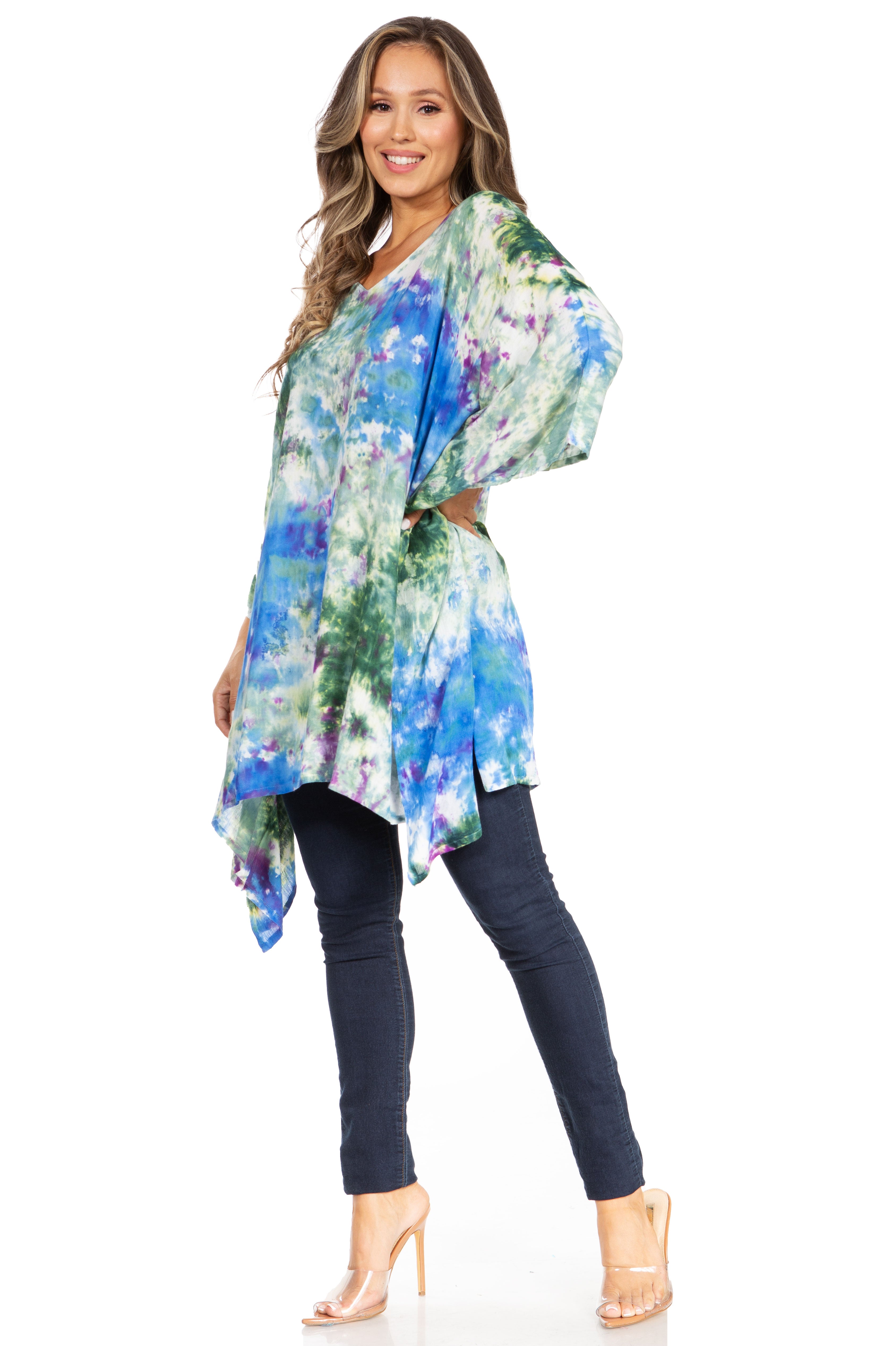 Woman wearing a colorful floral kimono-style top with dark jeans on a white background