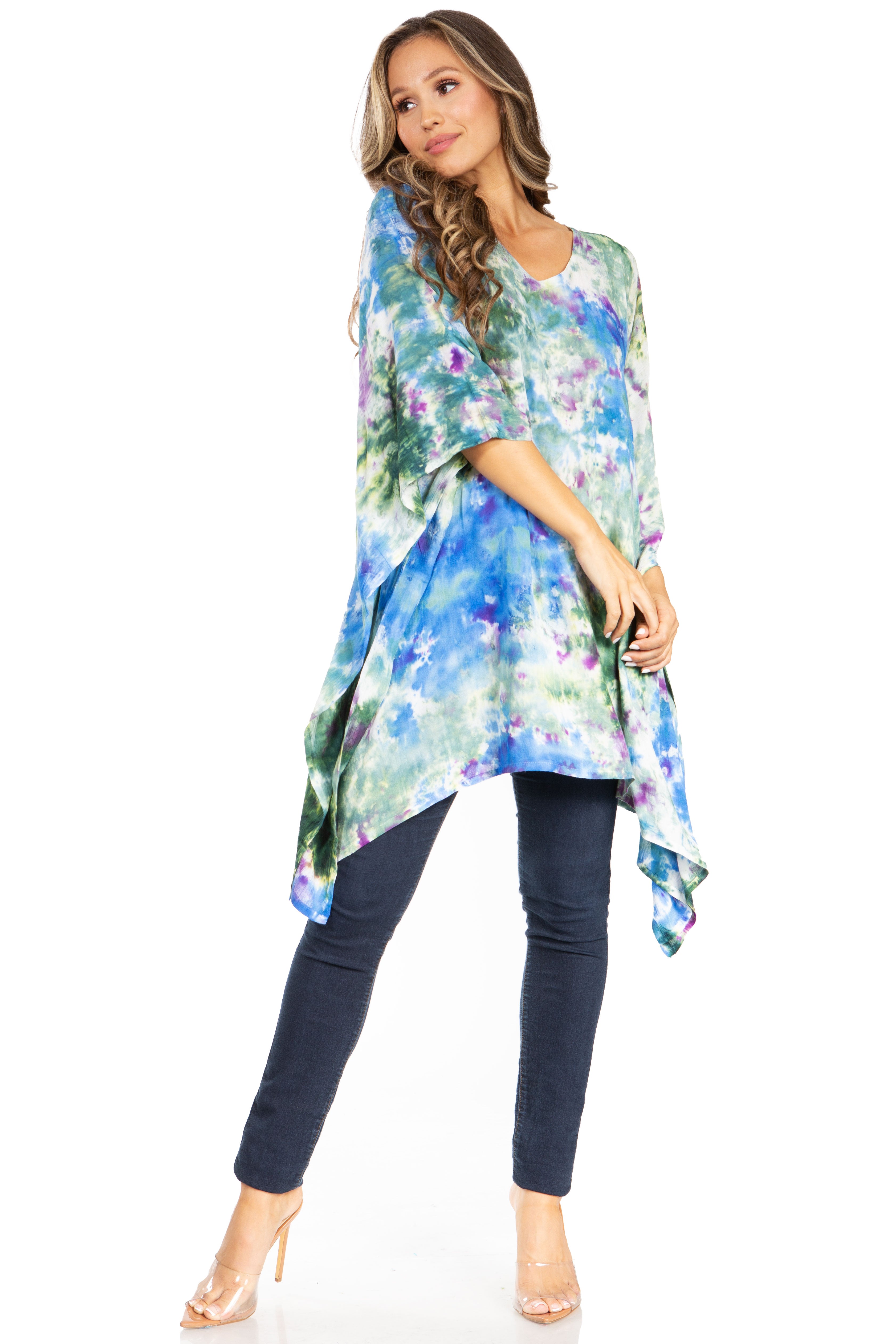 Woman wearing a colorful floral kimono-style top and dark jeans on a white background