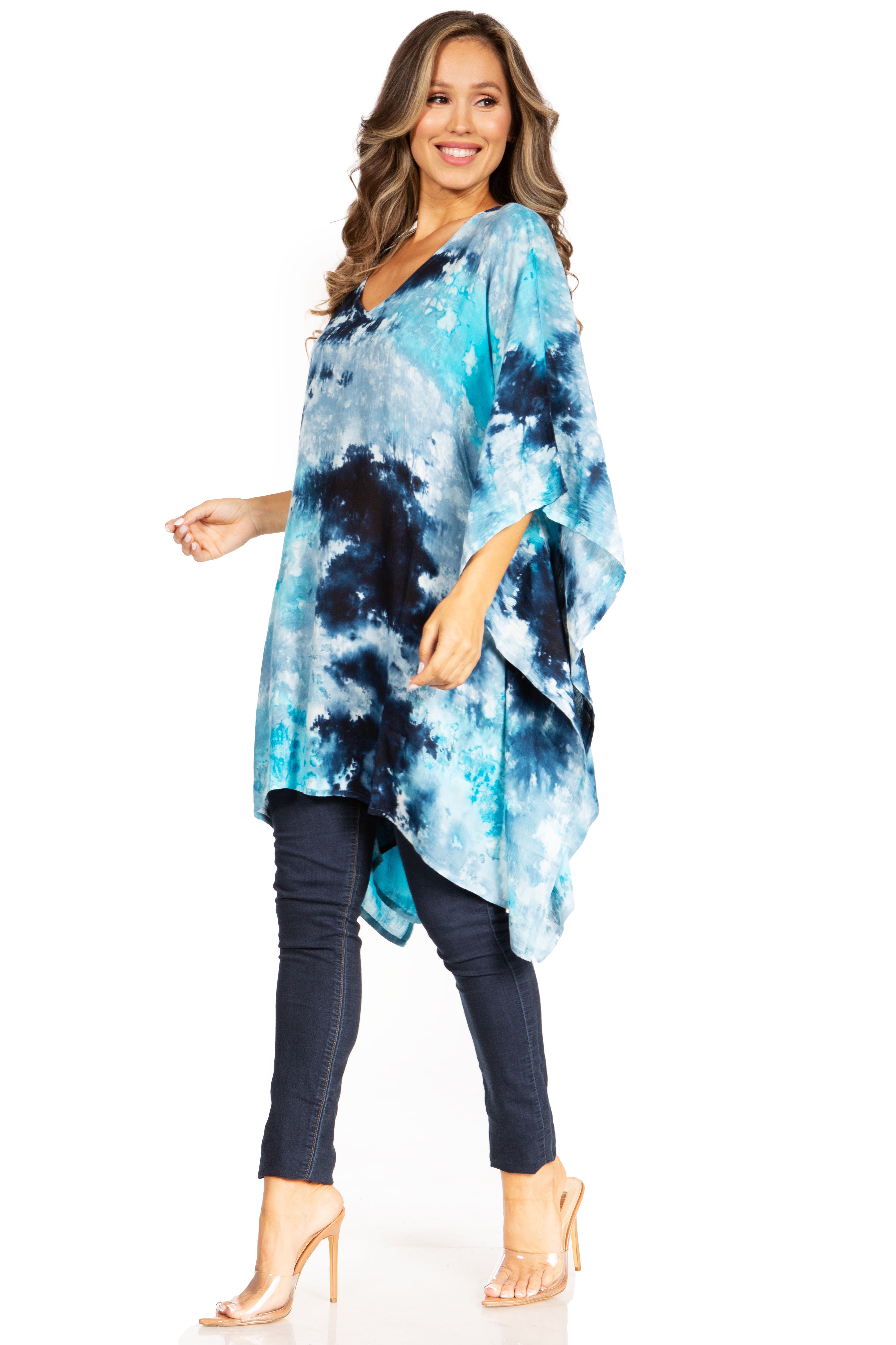 Woman wearing a blue tie-dye poncho over dark pants on a white background