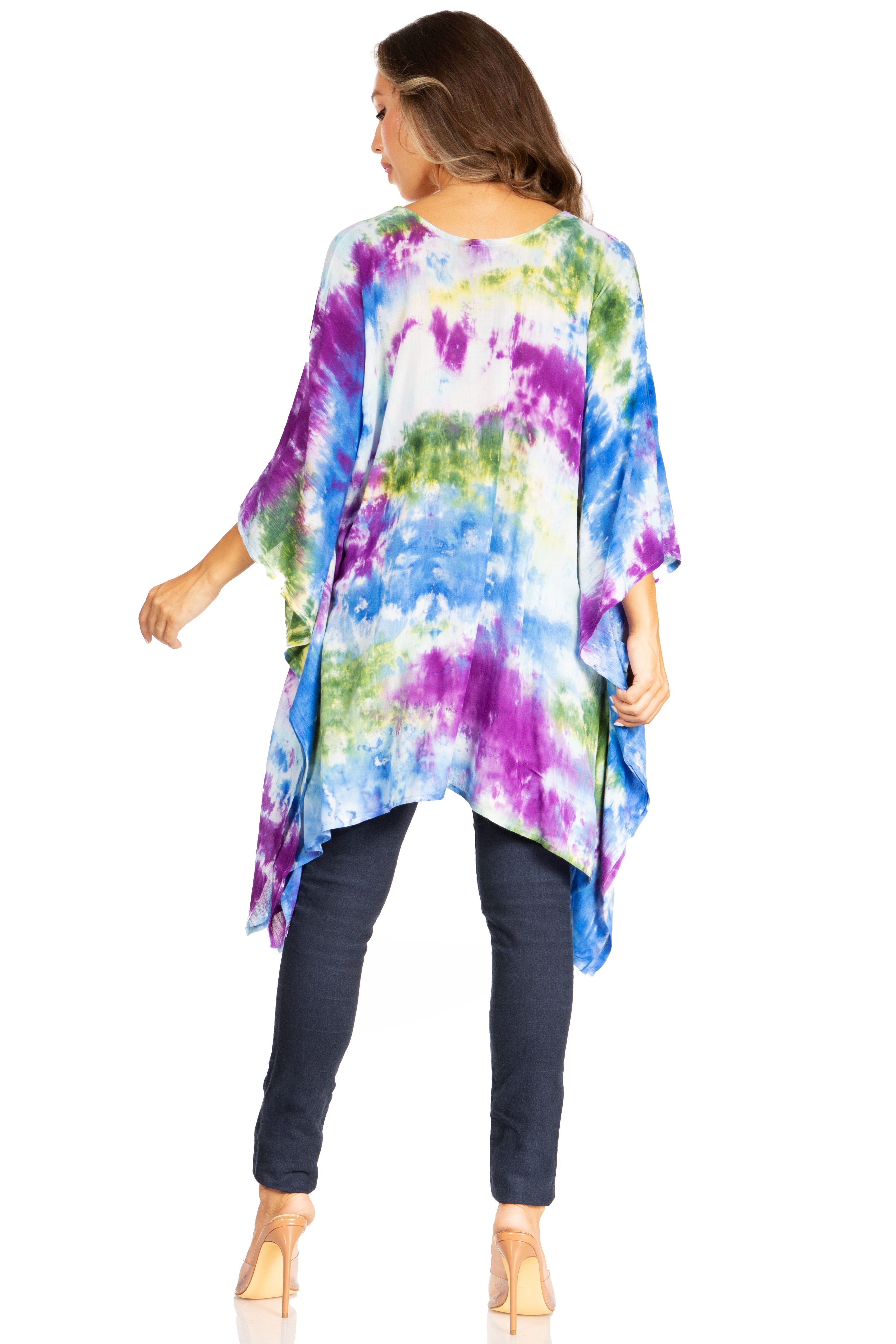 Woman wearing a colorful tie-dye tunic over dark jeans on a white background