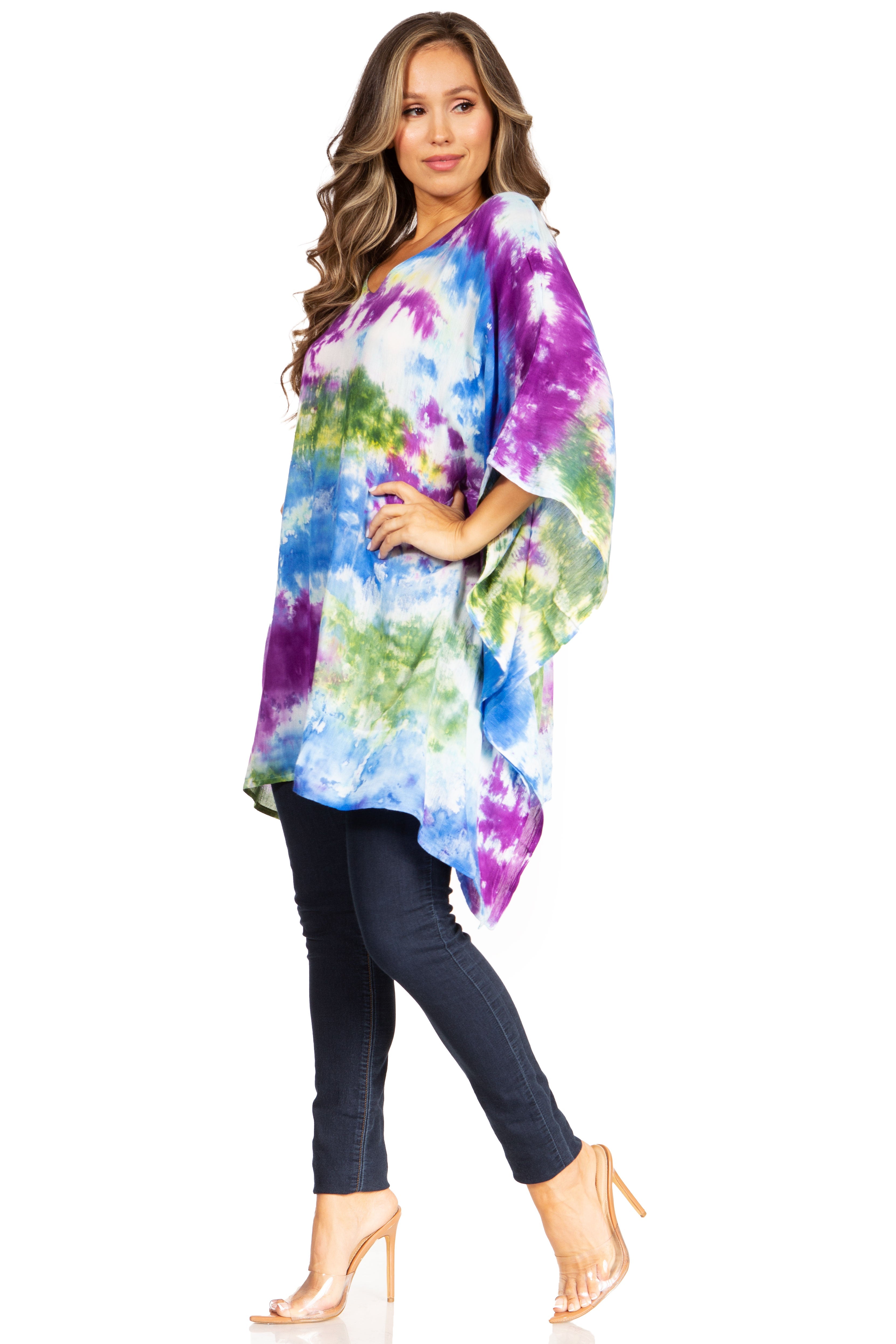 Woman wearing a colorful tie-dye top and dark jeans on a white background