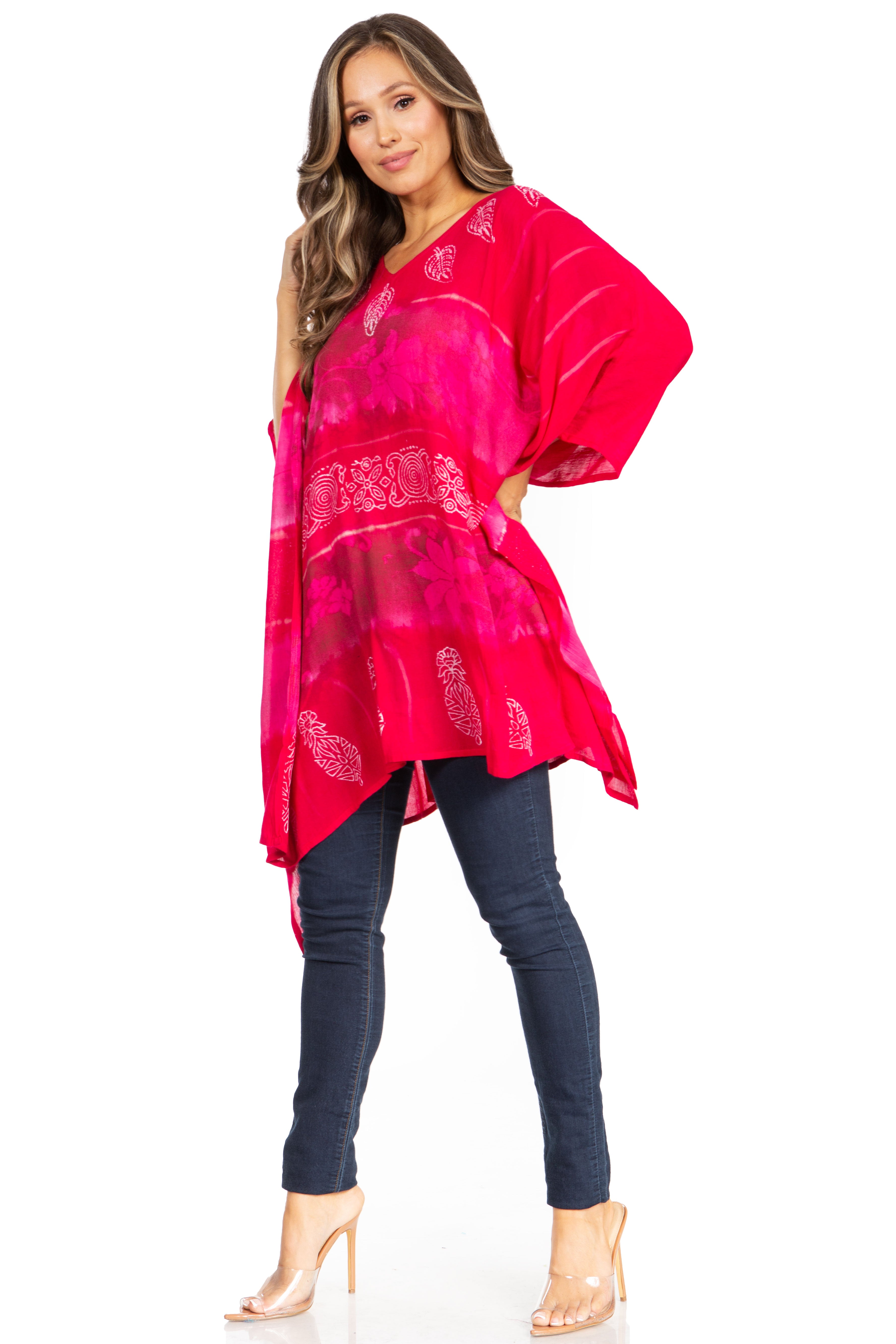 Woman wearing a bright pink patterned top and dark jeans on a white background