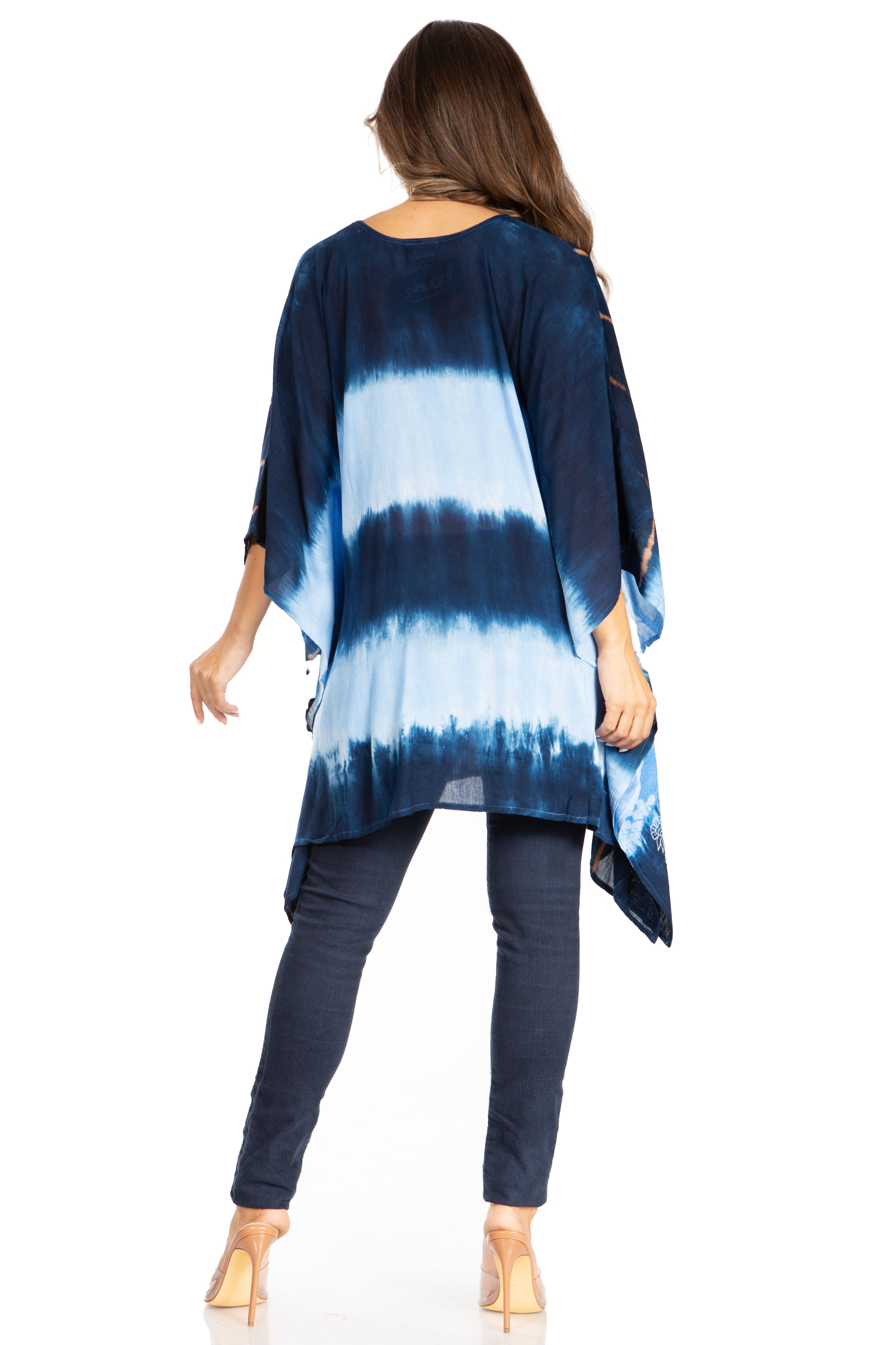 Woman wearing a blue tie-dye top and dark pants on a white background