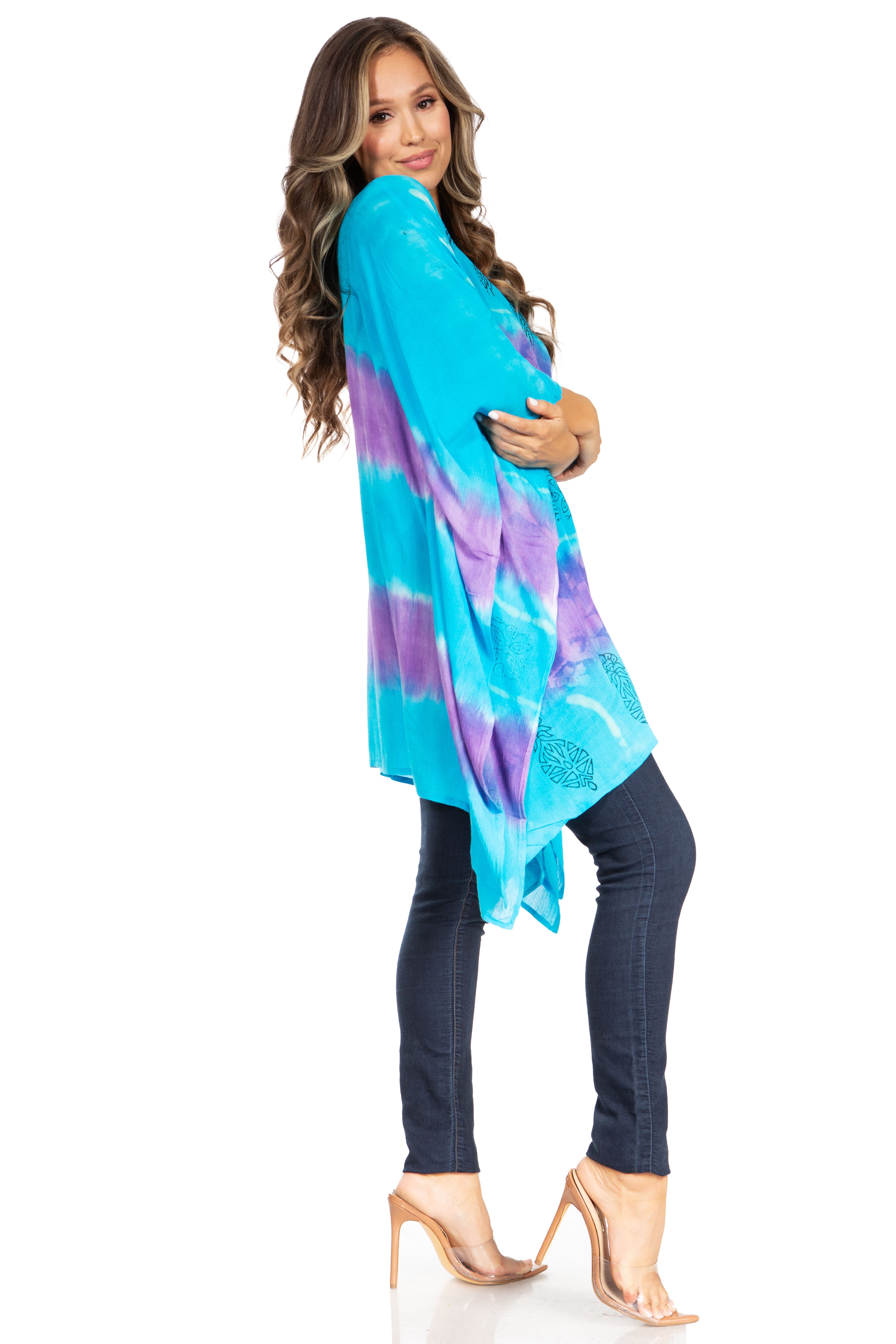 Woman wearing a colorful tie-dye shirt over a black top and pants on a white background