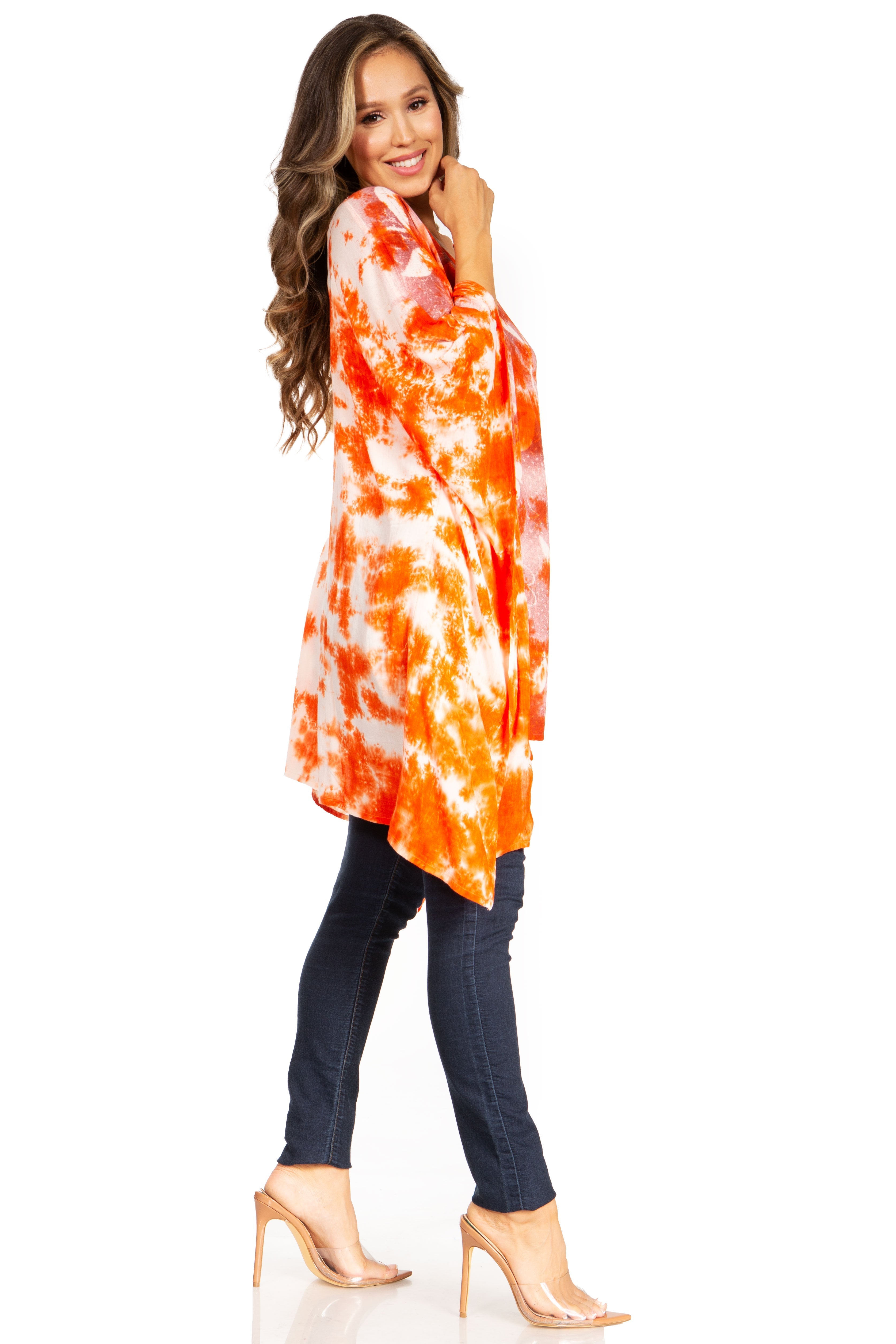 Woman wearing a tie-dye orange and white shirt with dark jeans on a white background