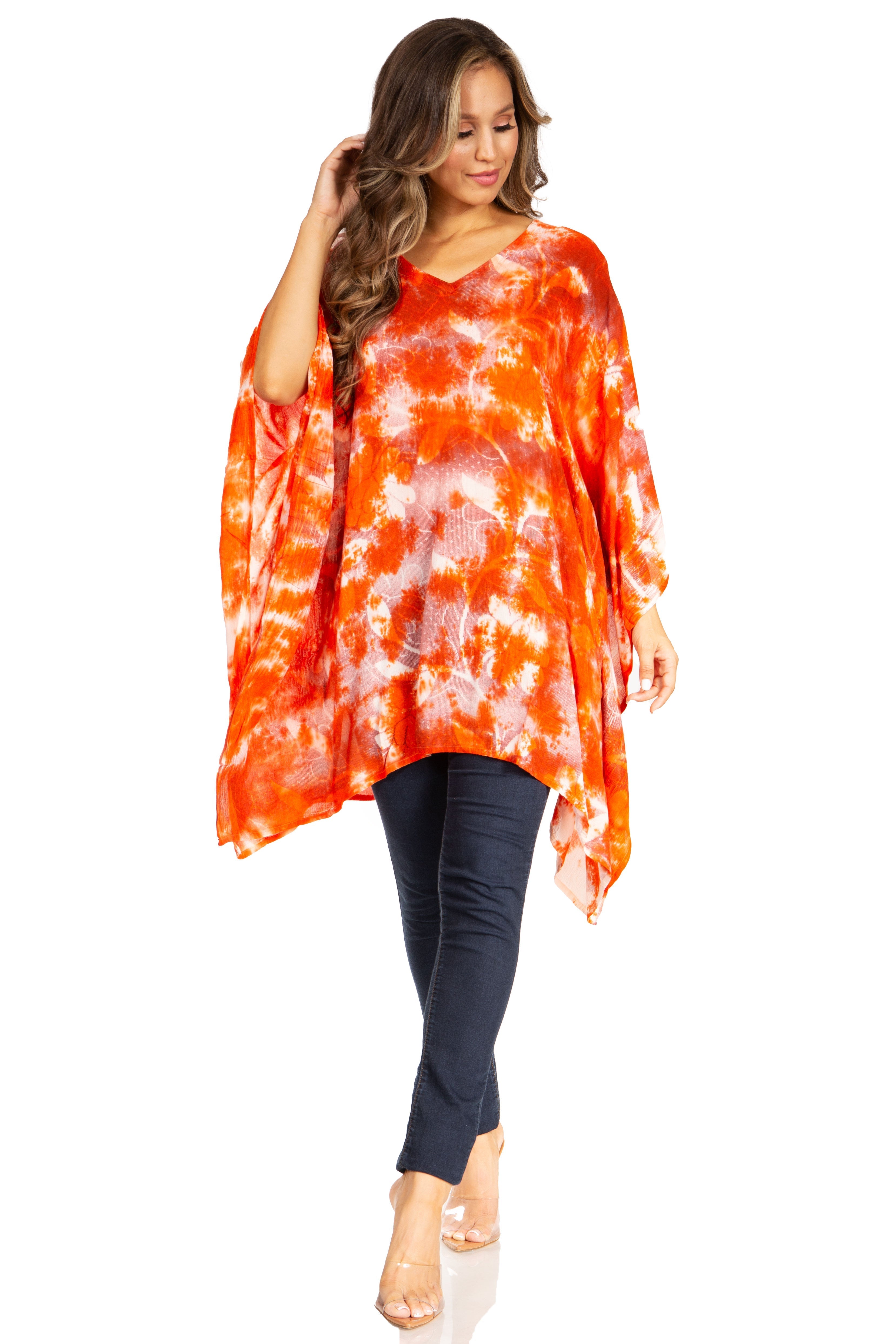 Woman wearing an orange and white tie-dye top with dark pants on a white background