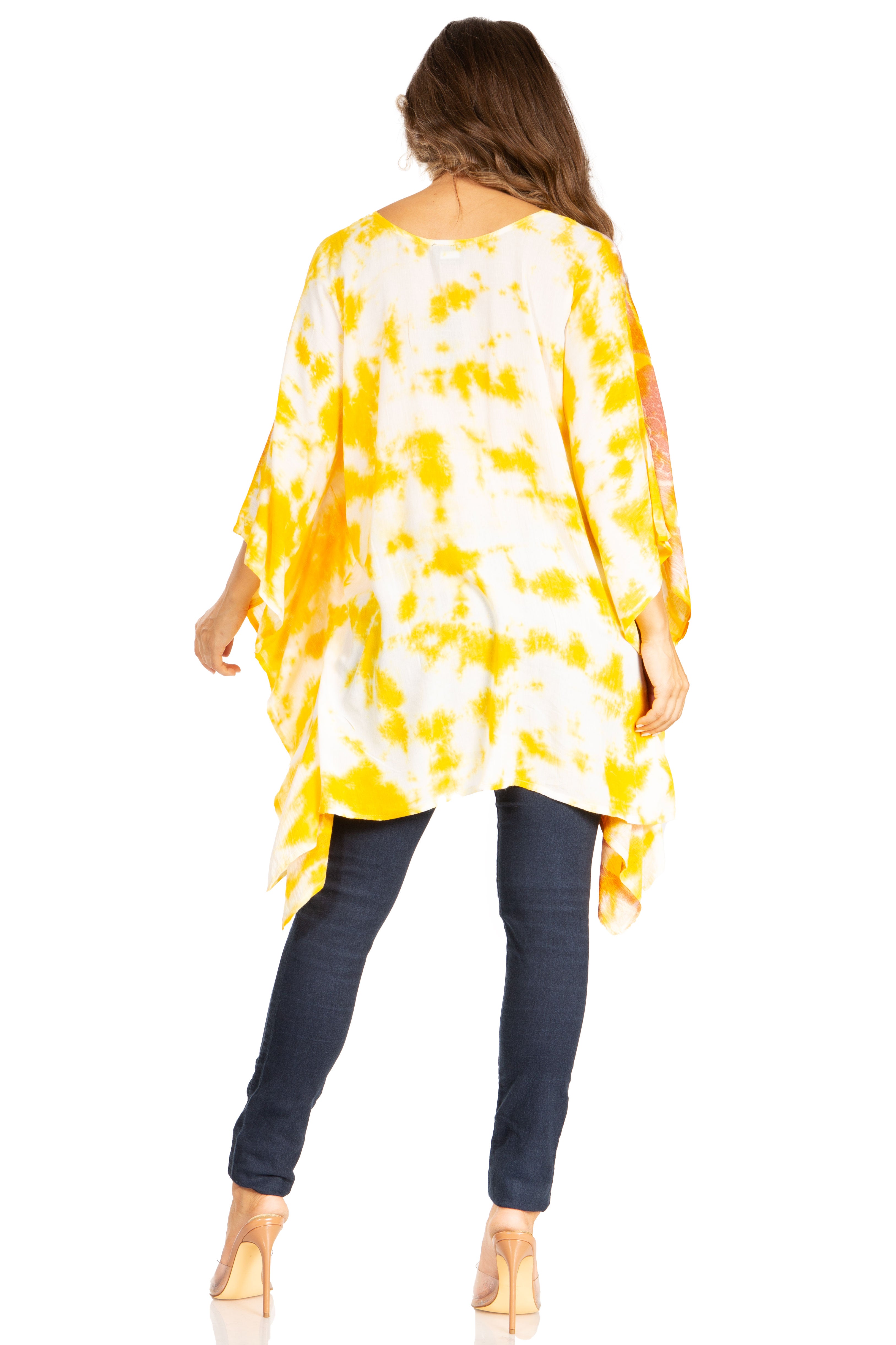 Woman wearing a yellow and white tie-dye shirt with dark jeans on a white background