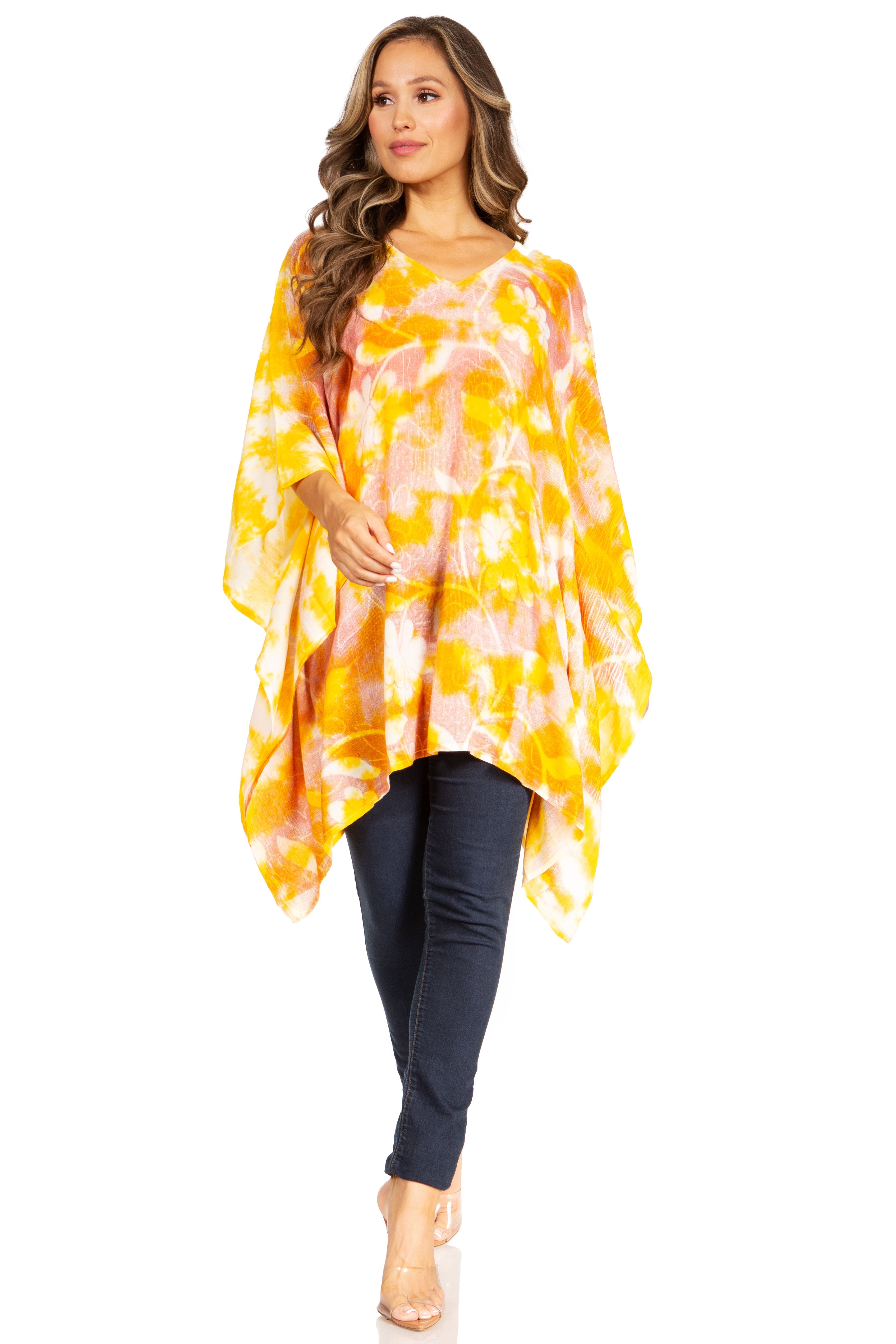 Woman wearing a yellow tie-dye poncho over a black top and pants on a white background