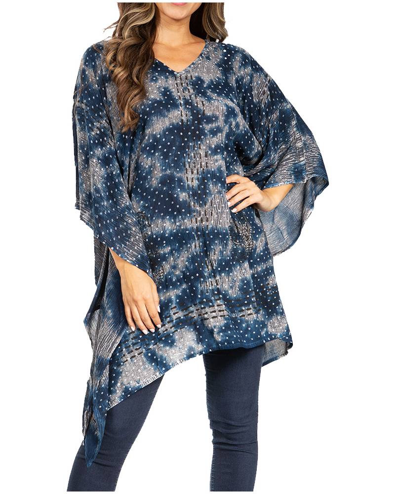 Woman wearing a blue tie-dye poncho over a plain top and jeans on a white background