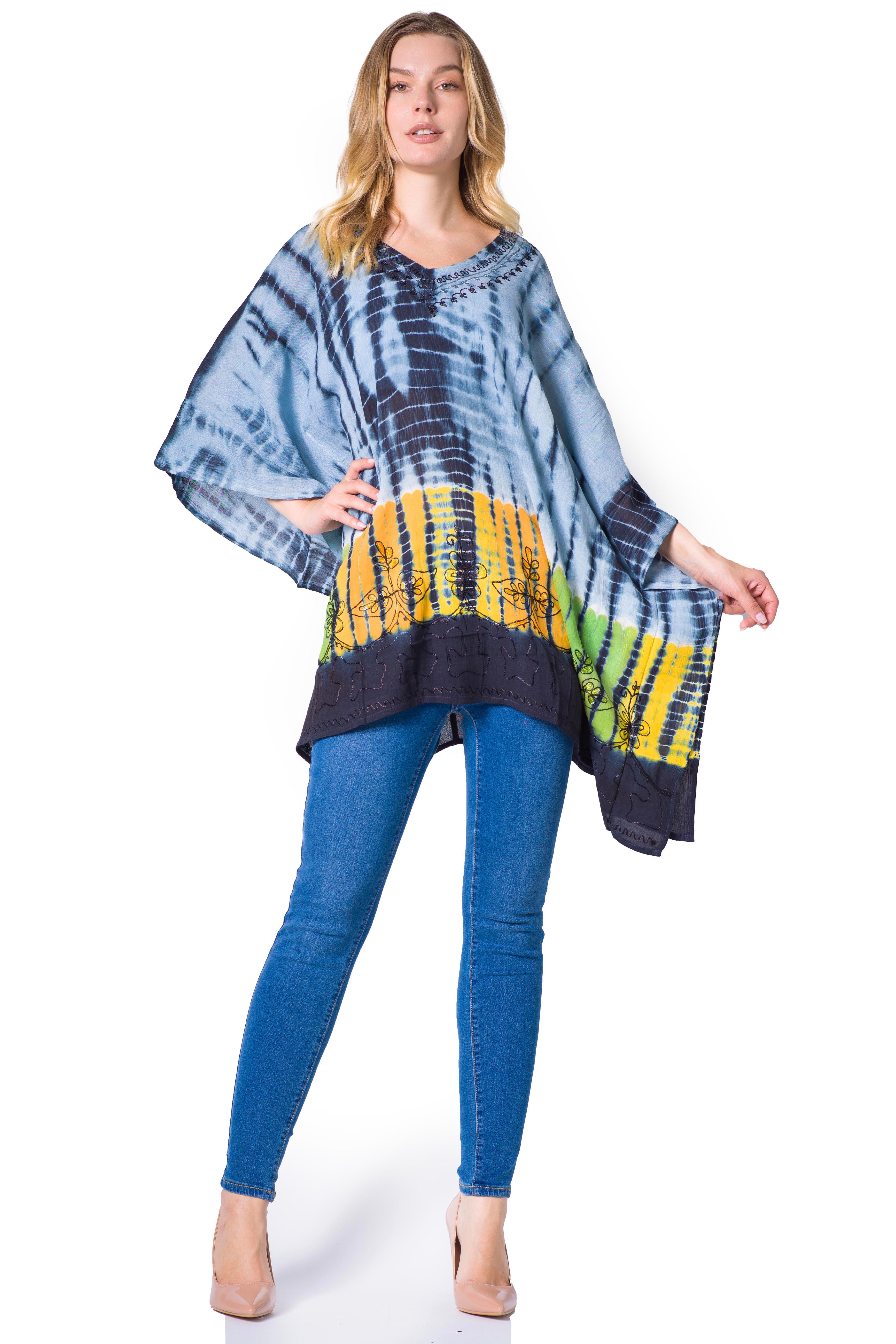 Woman wearing a tie-dye poncho with blue jeans on a white background
