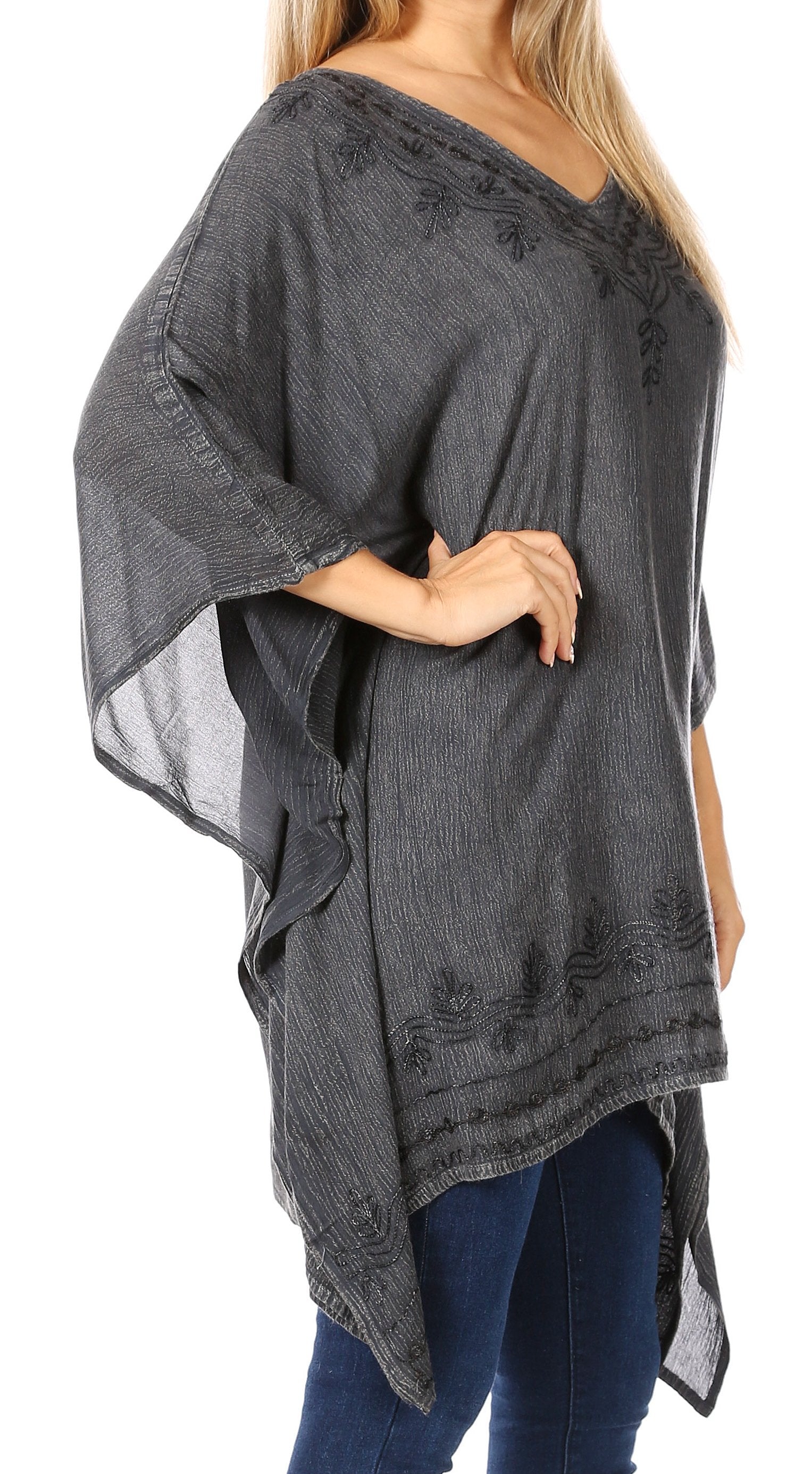 Woman wearing a dark gray, semi-sheer blouse with floral embroidery on a white background